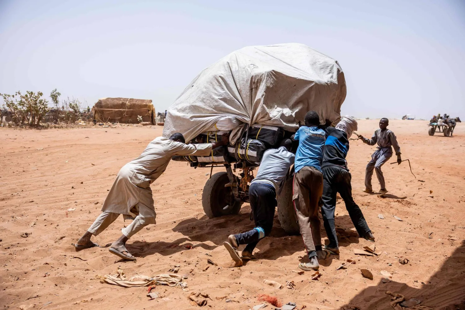Men push a stuck cart toward Sudan at the Adre border post on June 8, 2026. (Photo by Joris Bolomey / AFP)