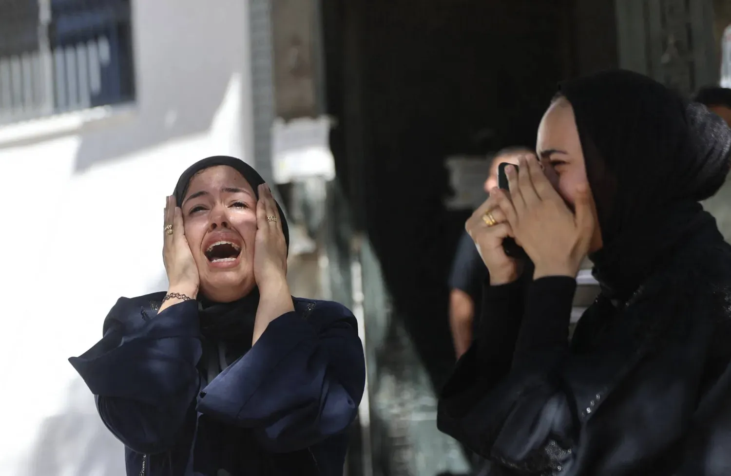 İsrail'in perşembe günü Gazze kentine düzenlediği hava saldırısında hayatını kaybeden bir kişinin cenaze töreni sırasında iki Filistinli kadın gözyaşları içinde ağıt yakıyor. (AFP)