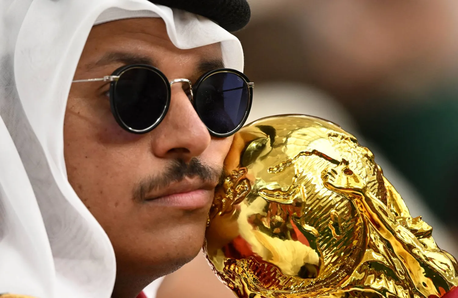 مشجع قطري ممسكاً بمجسم لكأس العالم في المدرجات (رويترز)