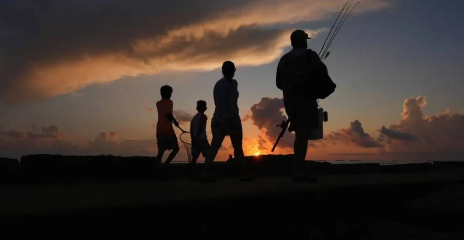 A family prepares to fish along a jetty at sunrise in Port Aransas, Texas, on Aug. 10, 2025. (AP Photo/Eric Gay, File)

