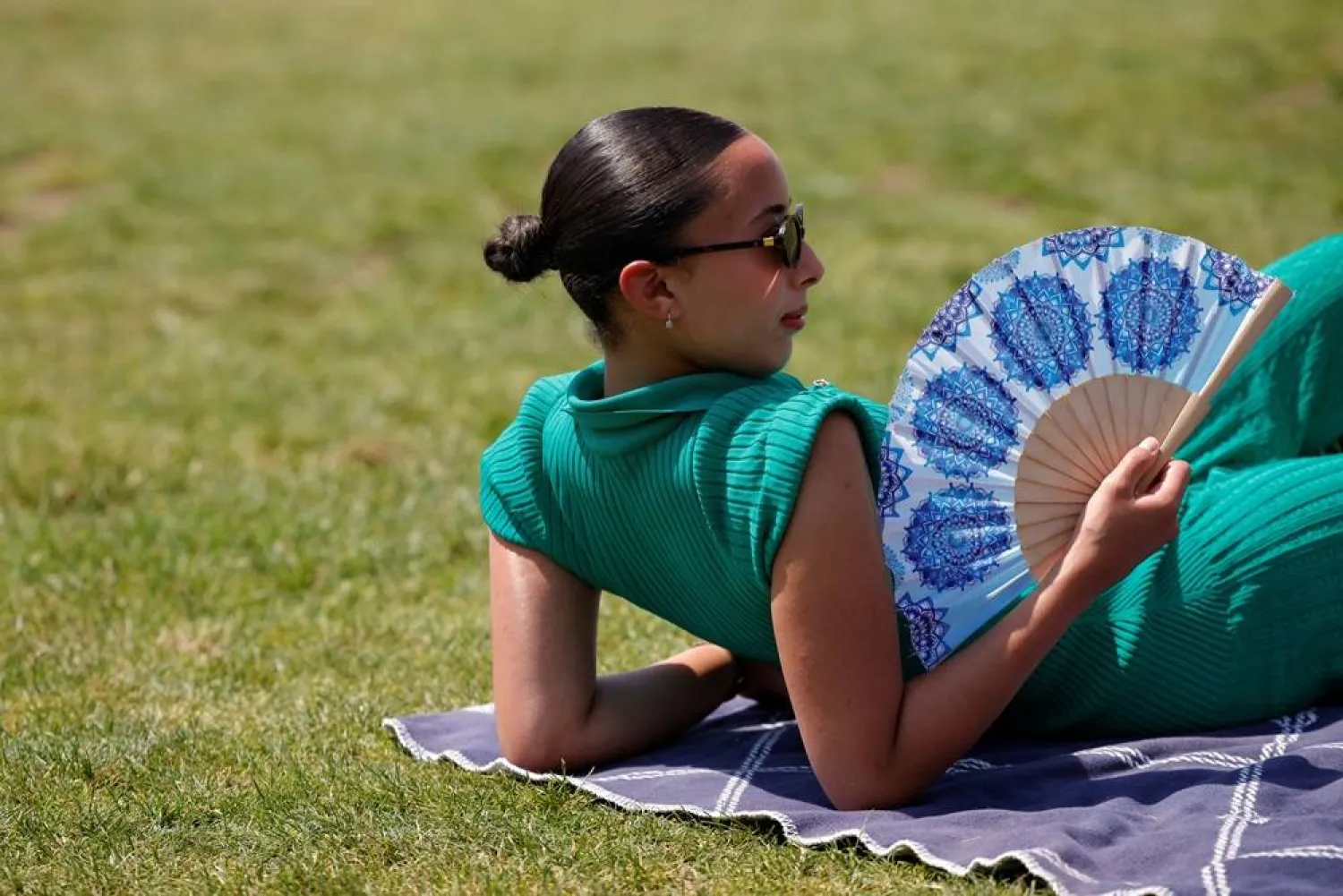  A woman with a hand fan sunbathes in the Tuileries Garden as temperatures rise in Paris during a second heatwave affecting a large of France, June 19, 2026. (Reuters)