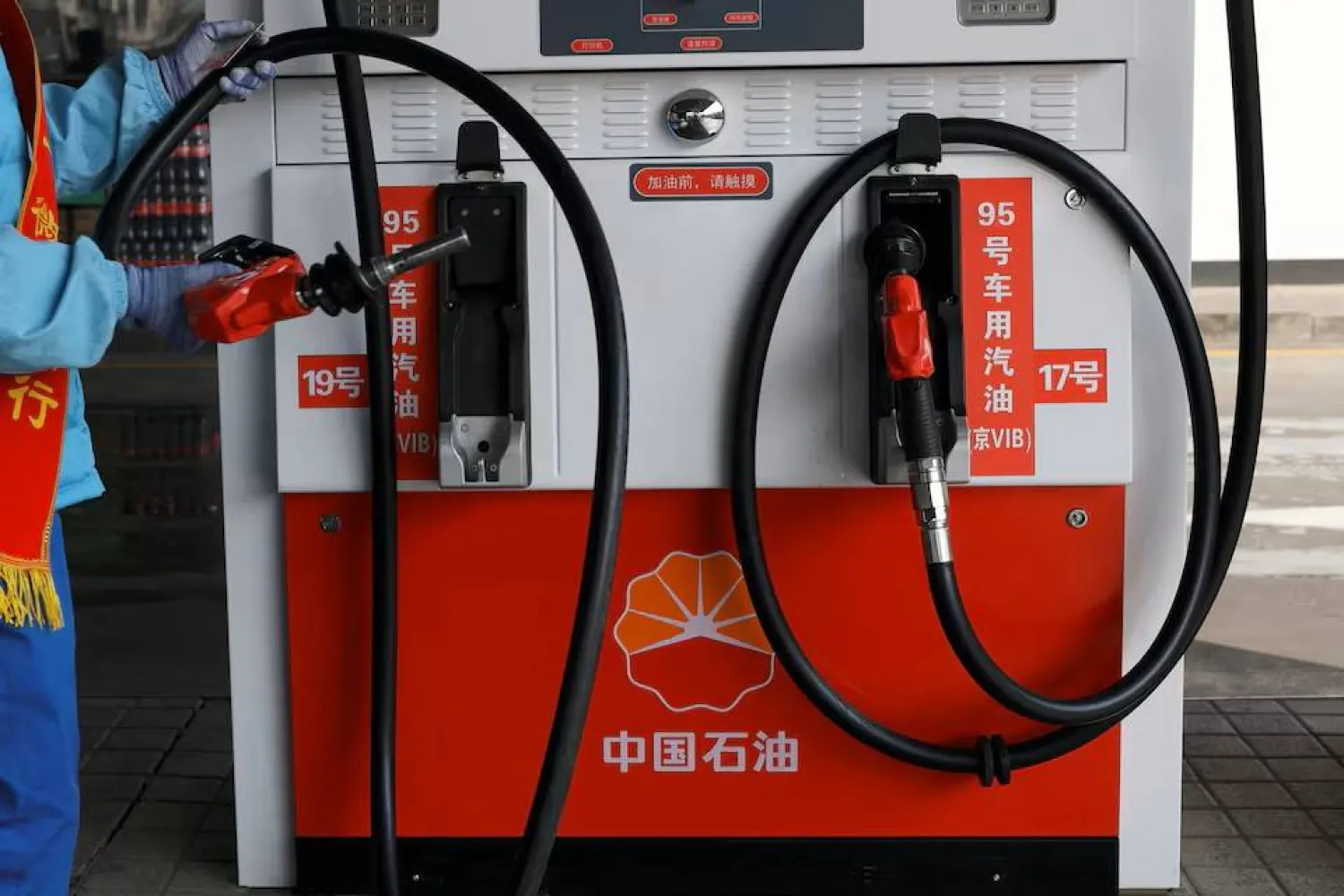 An attendant holds a petrol nozzle after refuelling a car at a PetroChina gas station in Beijing, China, March 10, 2026. REUTERS/Florence Lo