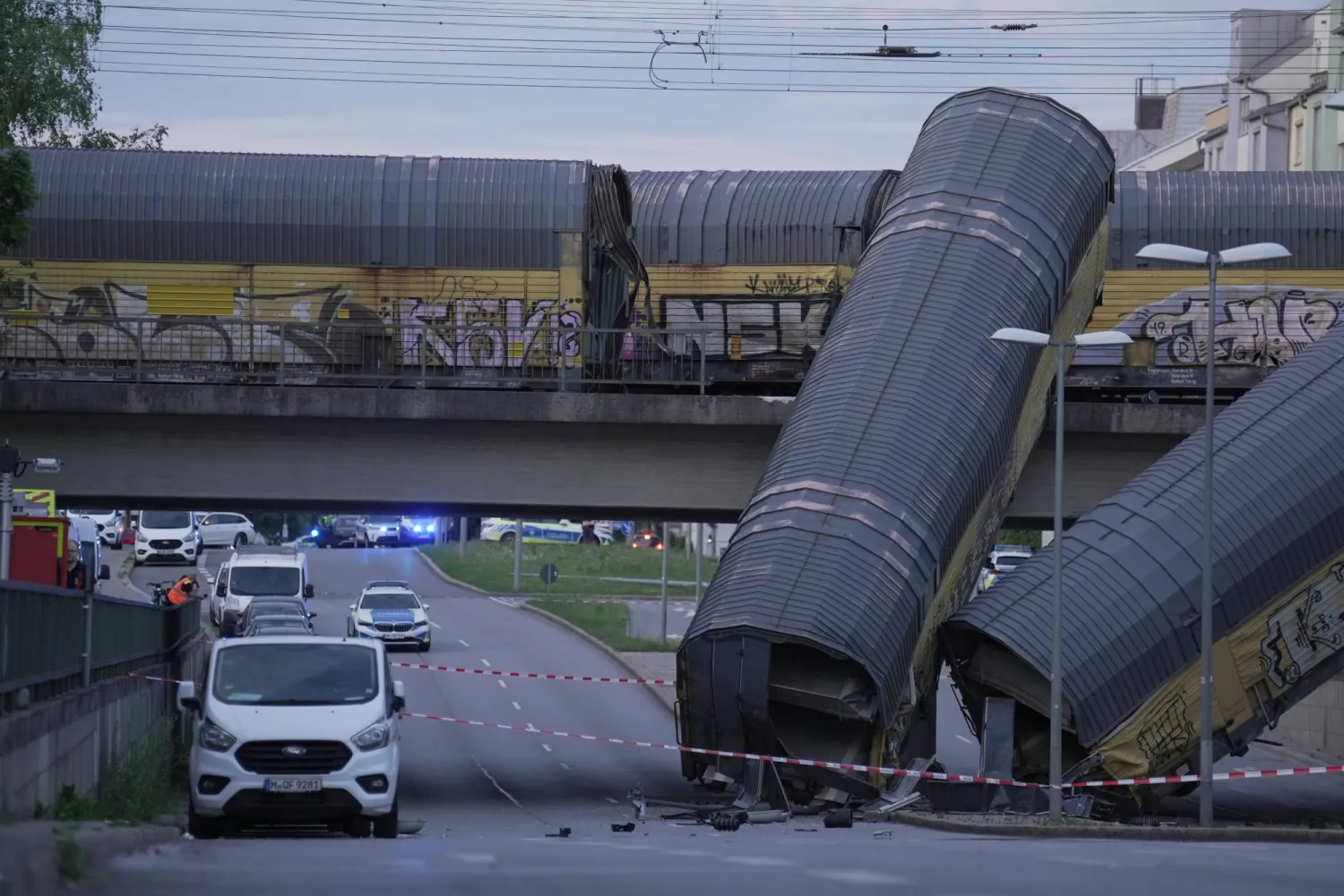 20 June 2026, Bavaria, Munich: Two freight-train cars lie on a road after falling off a bridge in Munich. Photo: Ehsan Monajati/dpa