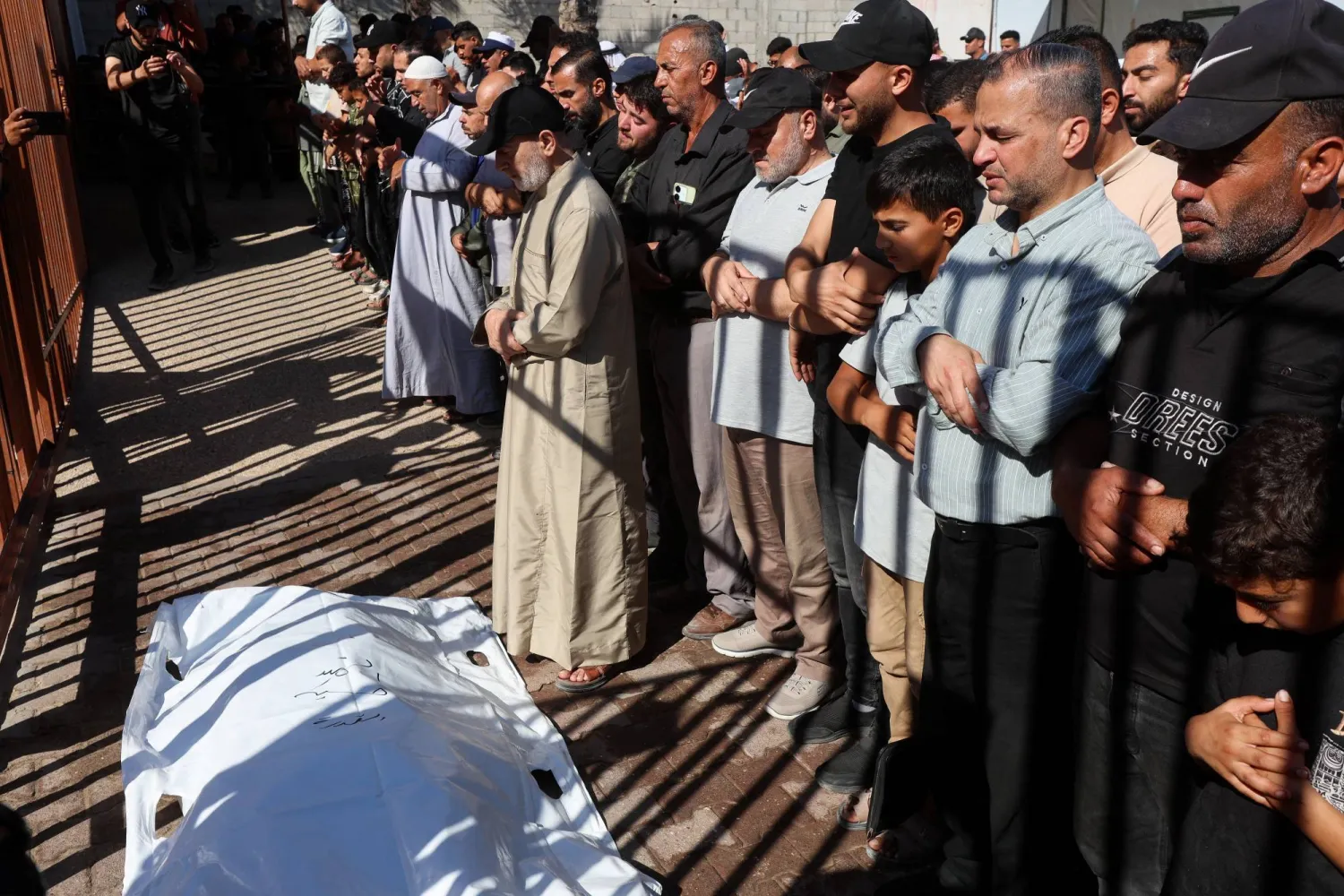 مشيعون يؤدون صلاة الجنازة على فلسطينيين قتلوا في ضربات إسرائيلية في خان يونس (رويترز)