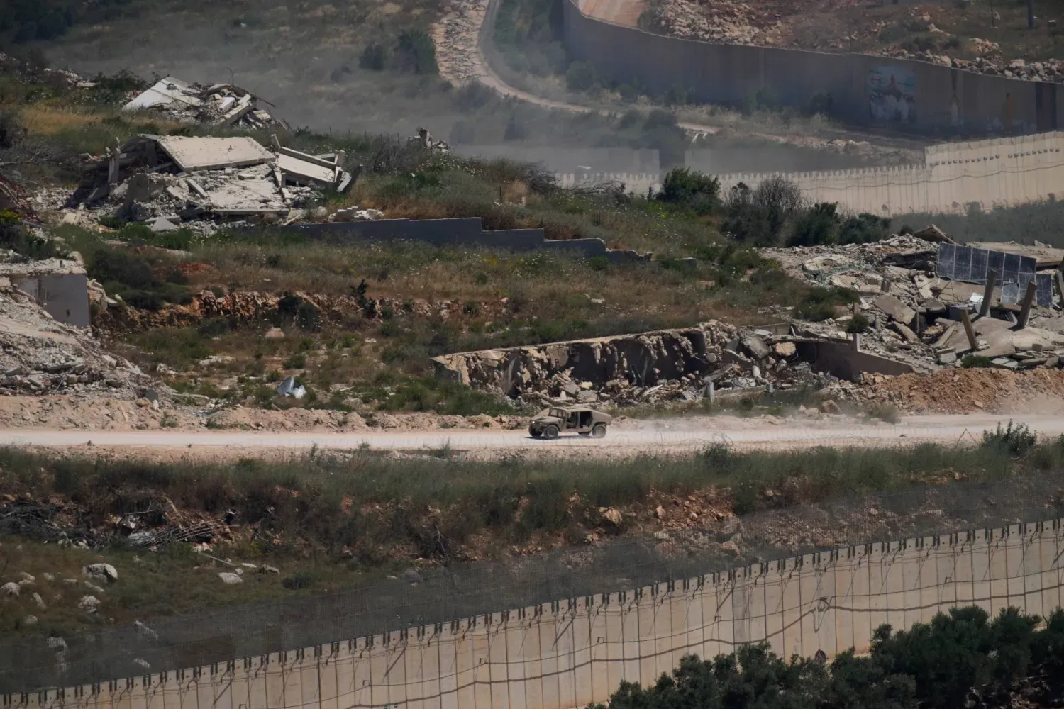 İsrail'e ait bir askeri araç, Lübnan'ın güneyindeki yıkılmış binaların yakınından geçiyor (AP)
