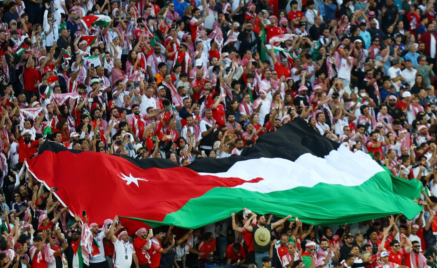 مشجعون يرفعون علم الأردن في المدرجات قبل المباراة (رويترز)