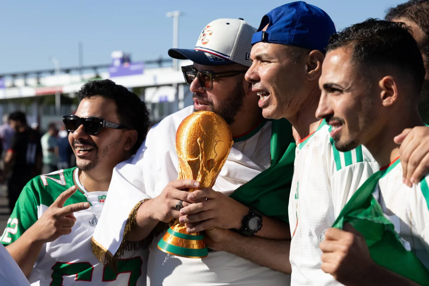 مشجعون من الجزائر يلتقطون صورة تذكارية مع نسخة طبق الأصل لكأس العالم (إ.ب.أ)