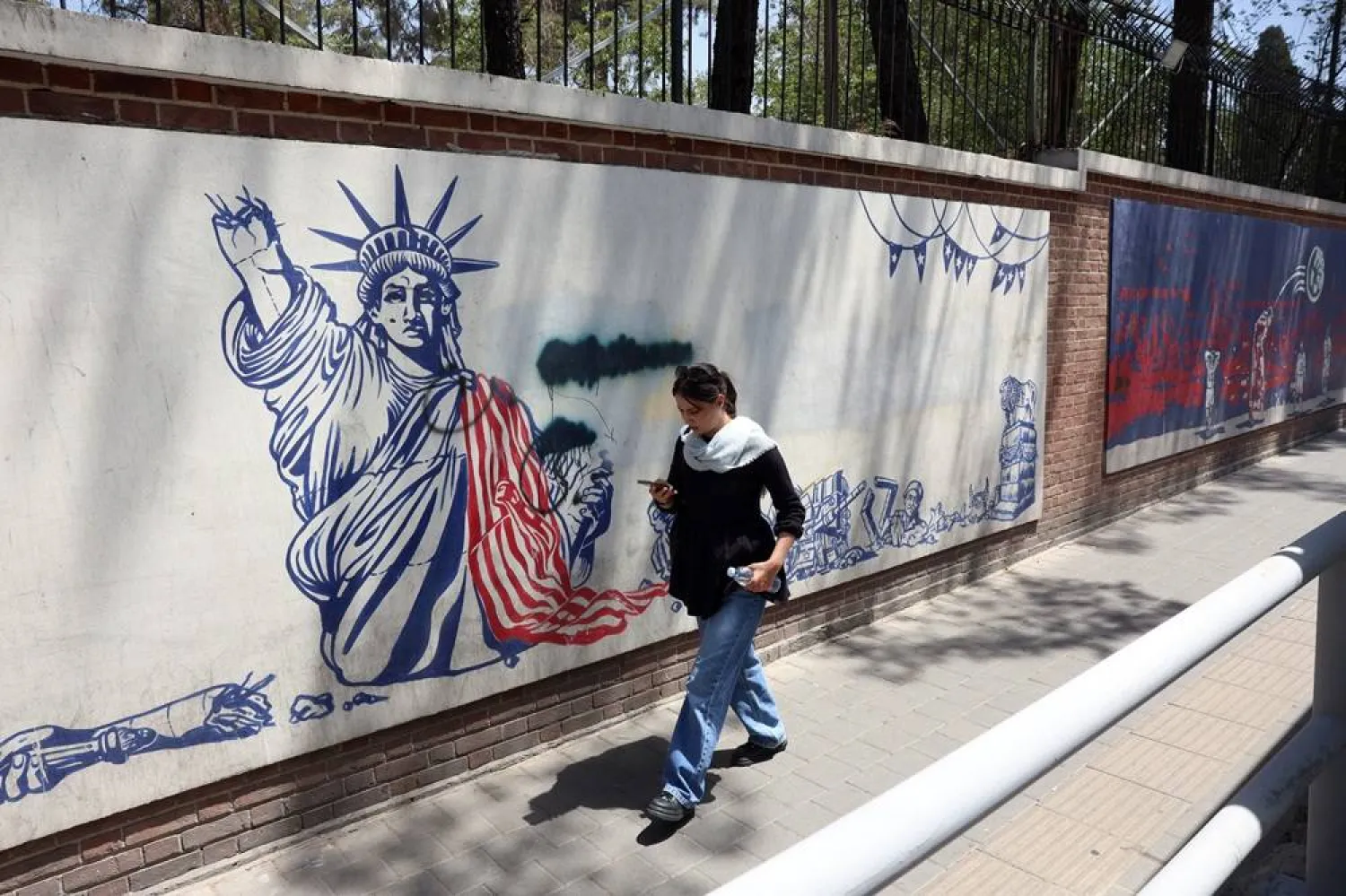 An Iranian woman walks past an anti-US mural next to the former US embassy in Tehran, Iran, 22 June 2026. (EPA)