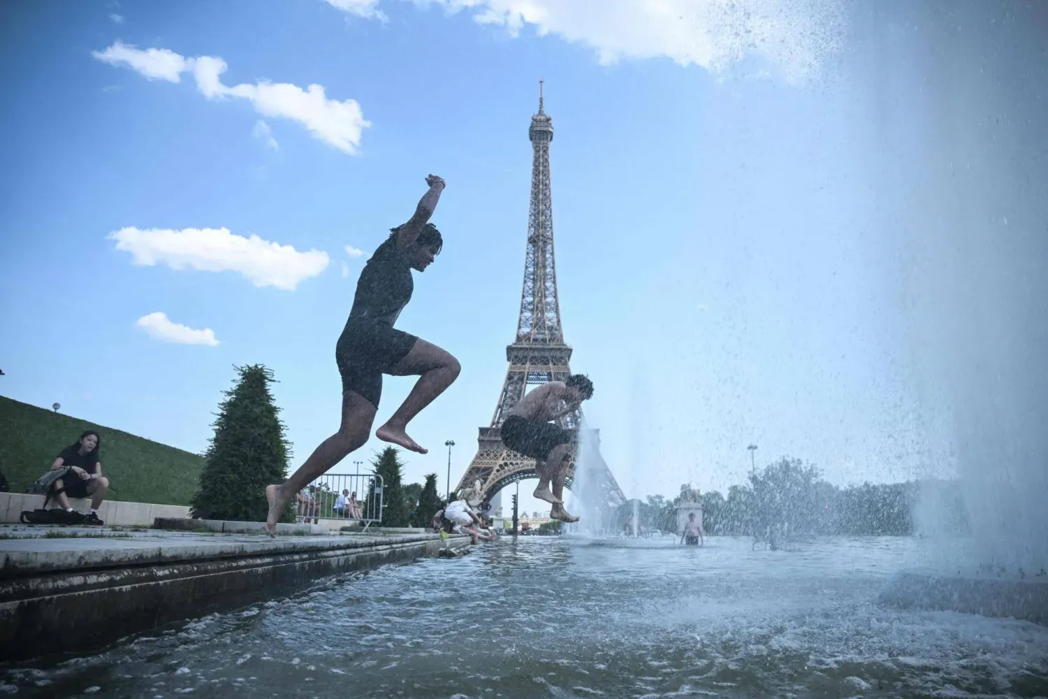 Paris'te etkisini sürdüren sıcak hava dalgası sırasında vatandaşlar, Eyfel Kulesi yakınındaki Trocadéro Çeşmesi'ne girerek serinlemeye çalışıyor. (AFP)