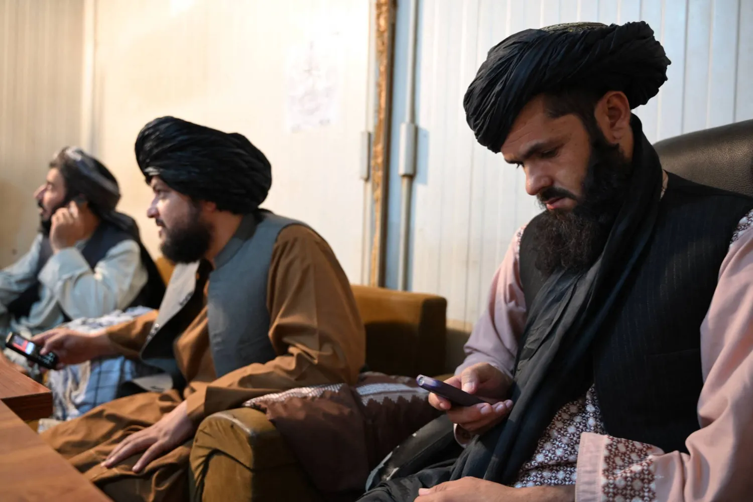 Taliban administrative staff use feature phones at the Department of Information and Culture building in Kandahar on June 22, 2026. (Photo by Sanaullah SEIAM / AFP)