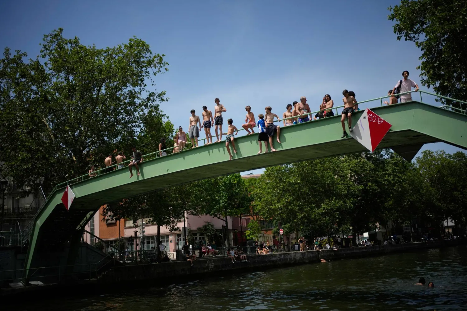 Parisians bath in the Canal Saint-Martin in Paris, as the national weather service, Meteo France, placed 54 departments, about half the country, under a red heat wave alert, Tuesday, June 23, 2026. (AP Photo/Christophe Ena )