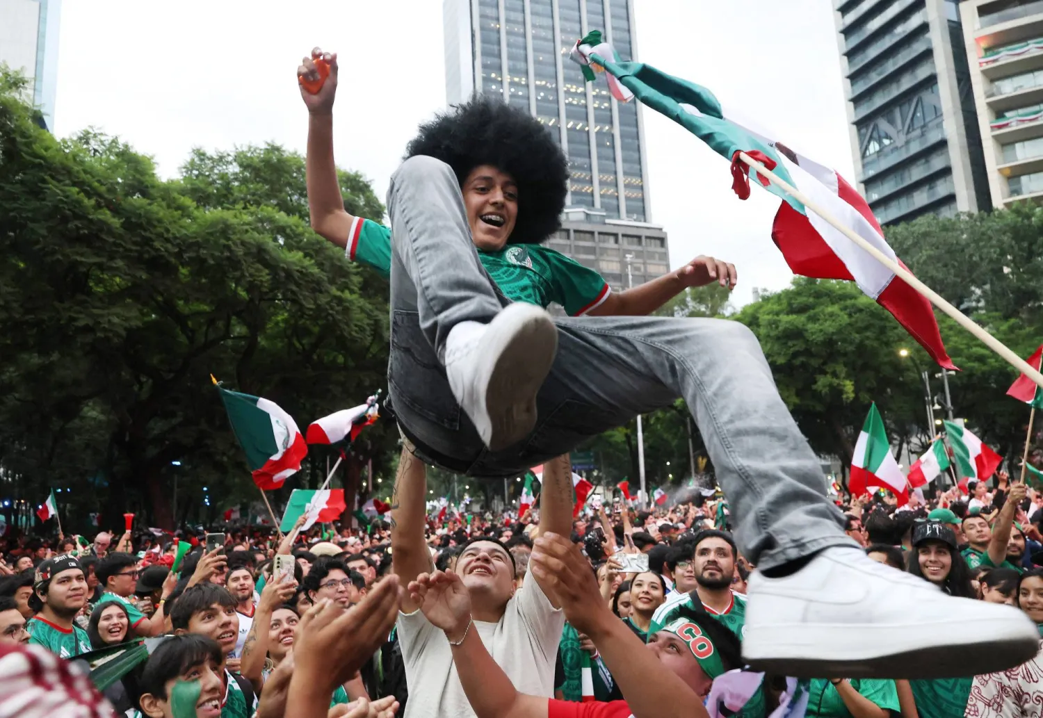 مشجع مكسيكي يُرفع عالياً في الهواء أثناء تجمّع الجماهير قبل المباراة (رويترز) 