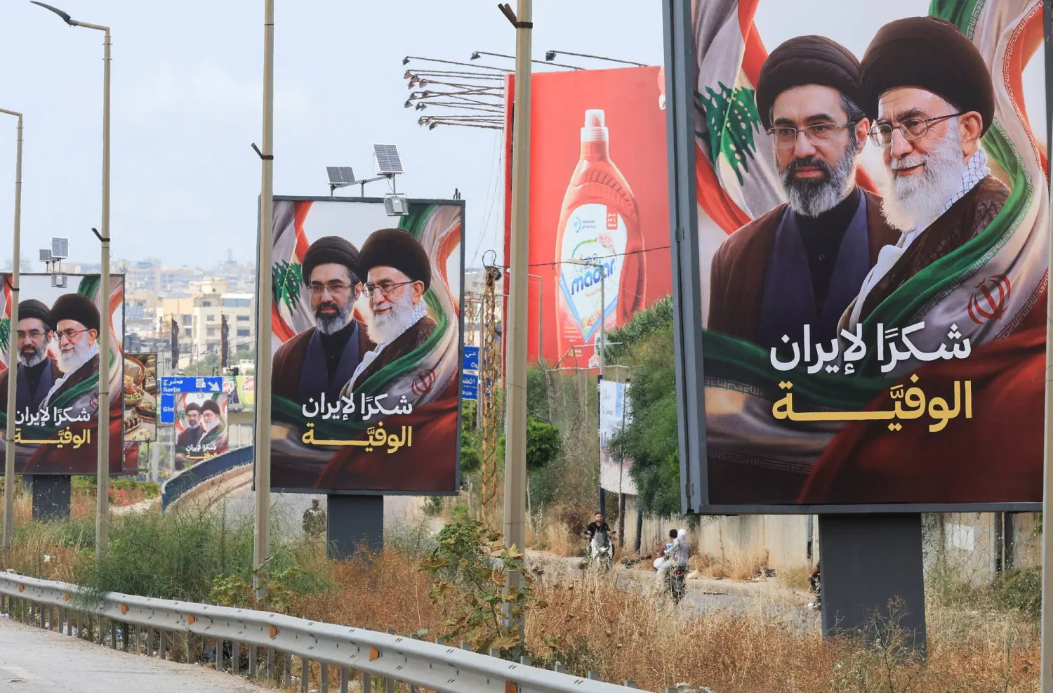 لافتات تحمل صور المرشد الإيراني مجتبى خامنئي ووالده علي خامنئي مرفقة بعبارة شكراً لإيران رفعت على طريق المطار باتجاه جنوب لبنان (رويترز)