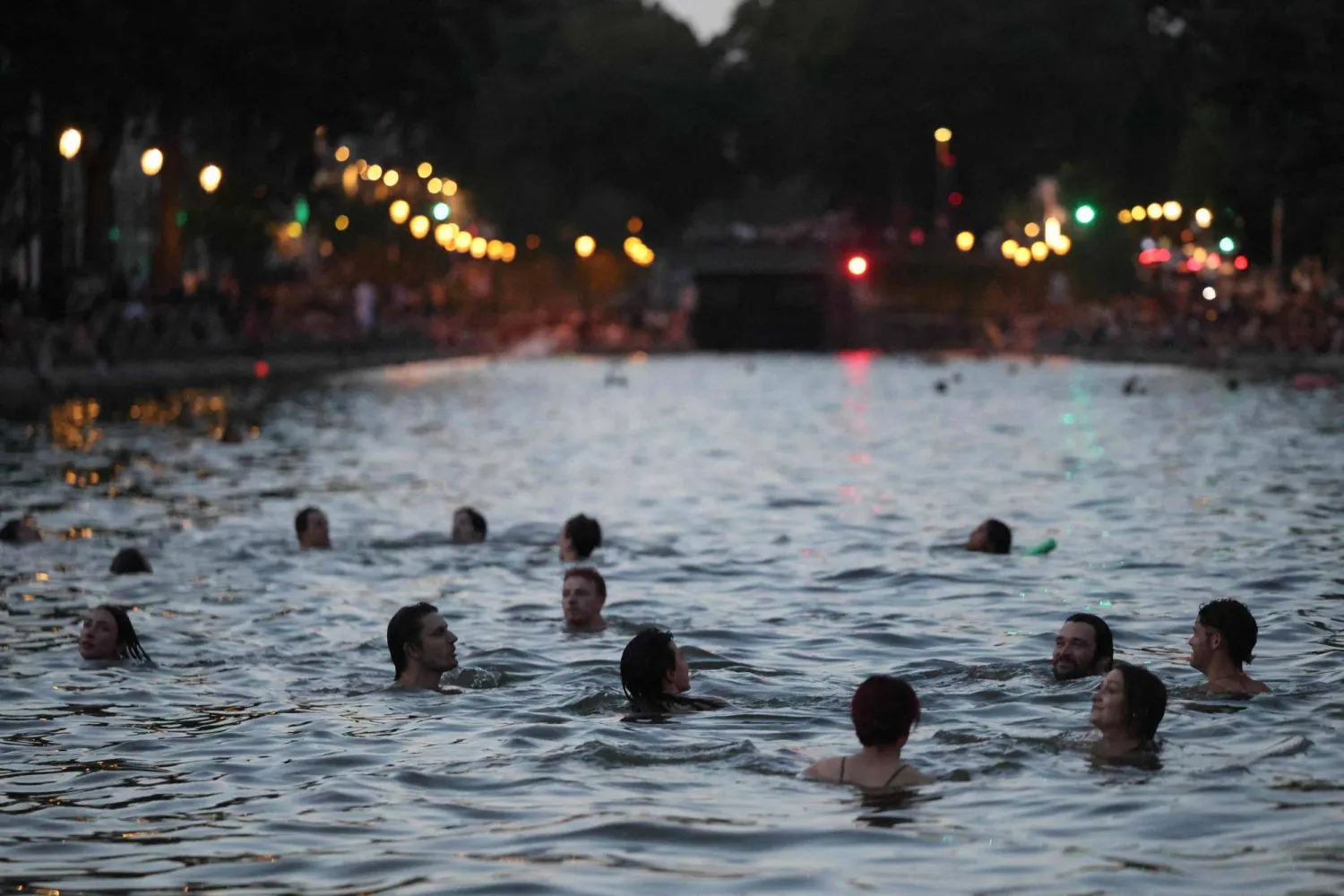 Youths cool down in the waters of the Canal Saint-Martin as France experiences a heatwave, in Paris on June 25, 2026. (Photo by Ludovic MARIN / AFP)