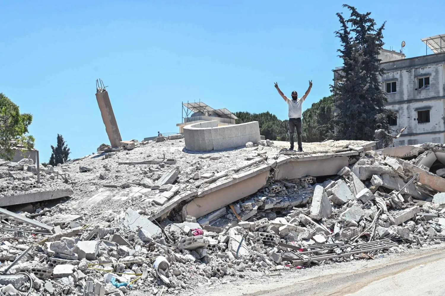 أحد سكان جنوب لبنان يرفع إشارة النصر بينما يقف فوق أنقاض منزله الذي دمرته غارات إسرائيلية (أ.ف.ب)