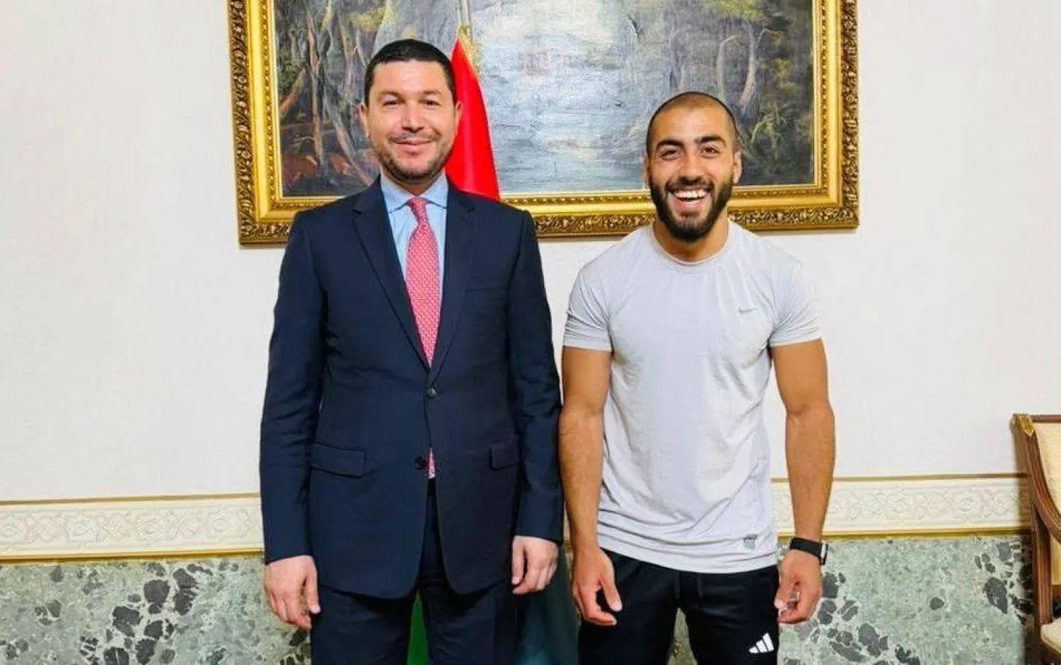 السفير الليبي لدى إيطاليا مع أحد المواطنين المفرج عنهم بمقر السفارة في روما الجمعة (صفحة السفارة)