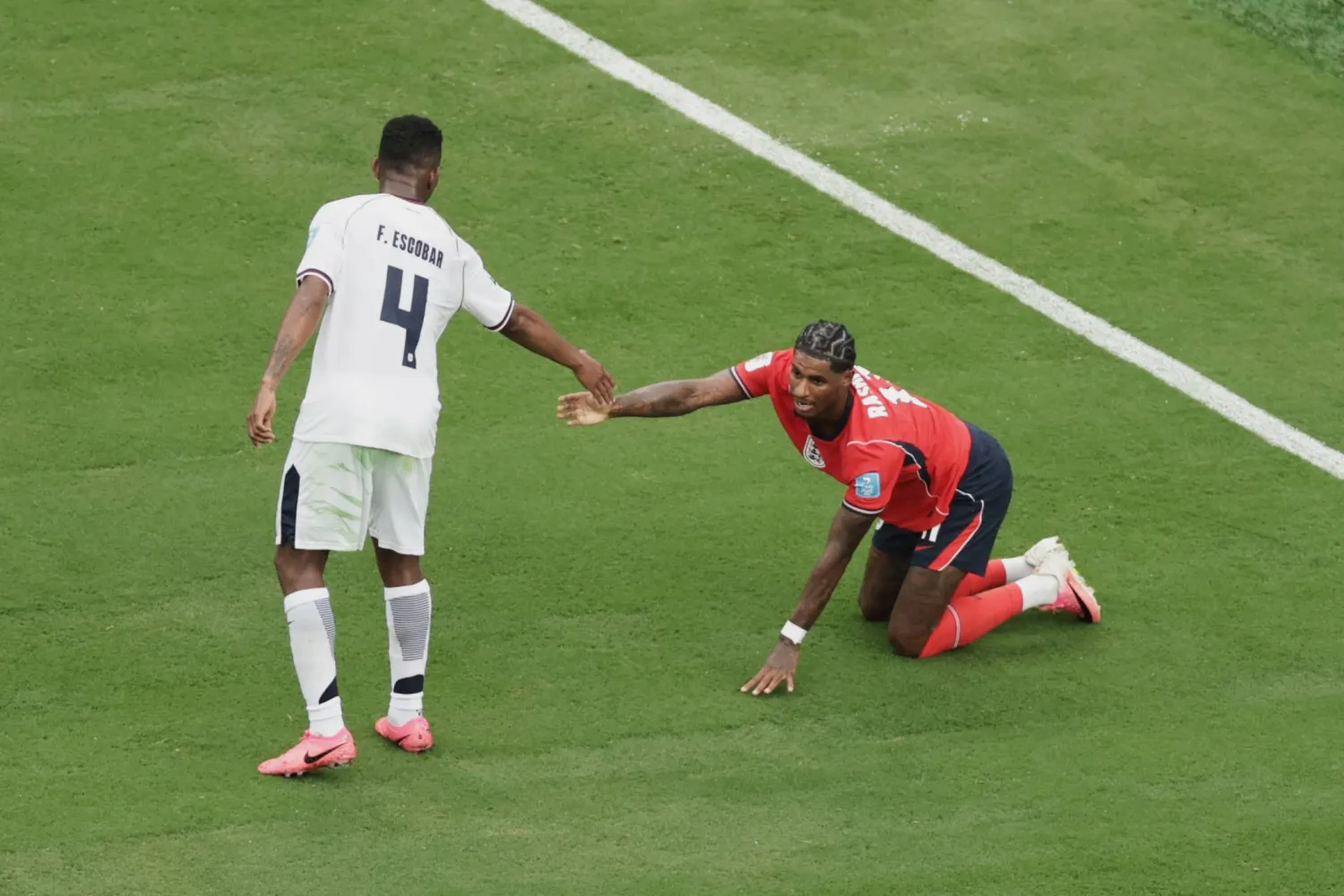 يساعد لاعب بنما فيدل إسكوبار (4) اللاعب الإنجليزي ماركوس راشفورد (11) على النهوض (أ.ب) 