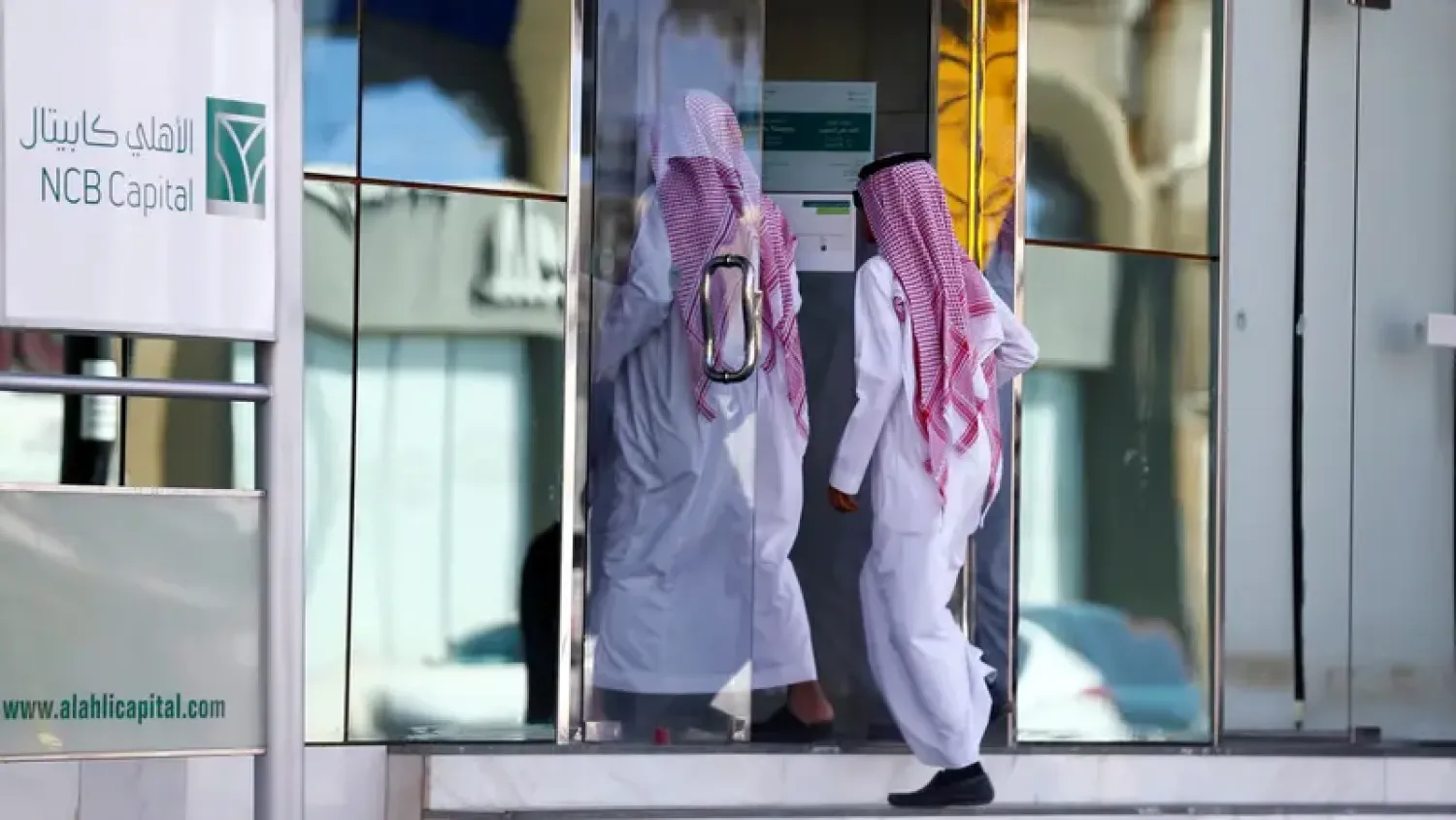أفراد يدخلون أحد فروع «البنك الأهلي» في السعودية (رويترز)
