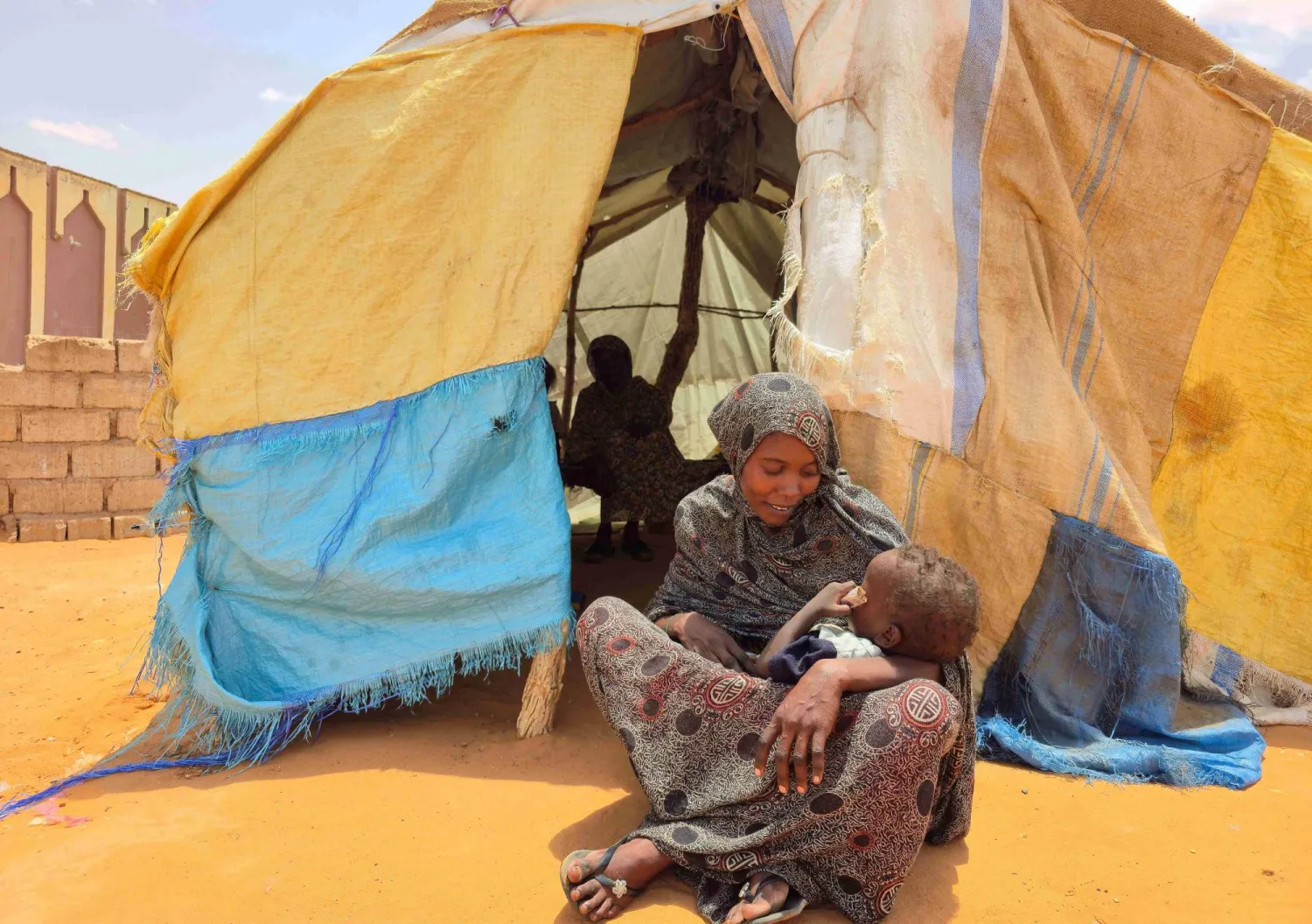 سودانية تجلس مع طفلها في مخيم للنازحين قرب مدينة الأبيض - 25 يونيو 2026 (أ.ف.ب)