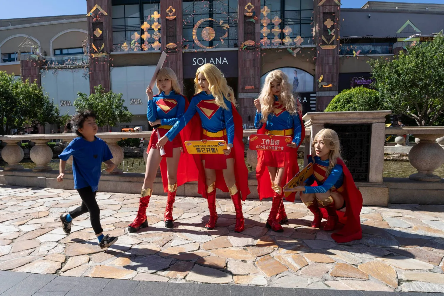 A child runs past promoters for the Supergirl movie at a mall in Beijing, Saturday, June 20, 2026. (AP Photo/Ng Han Guan)