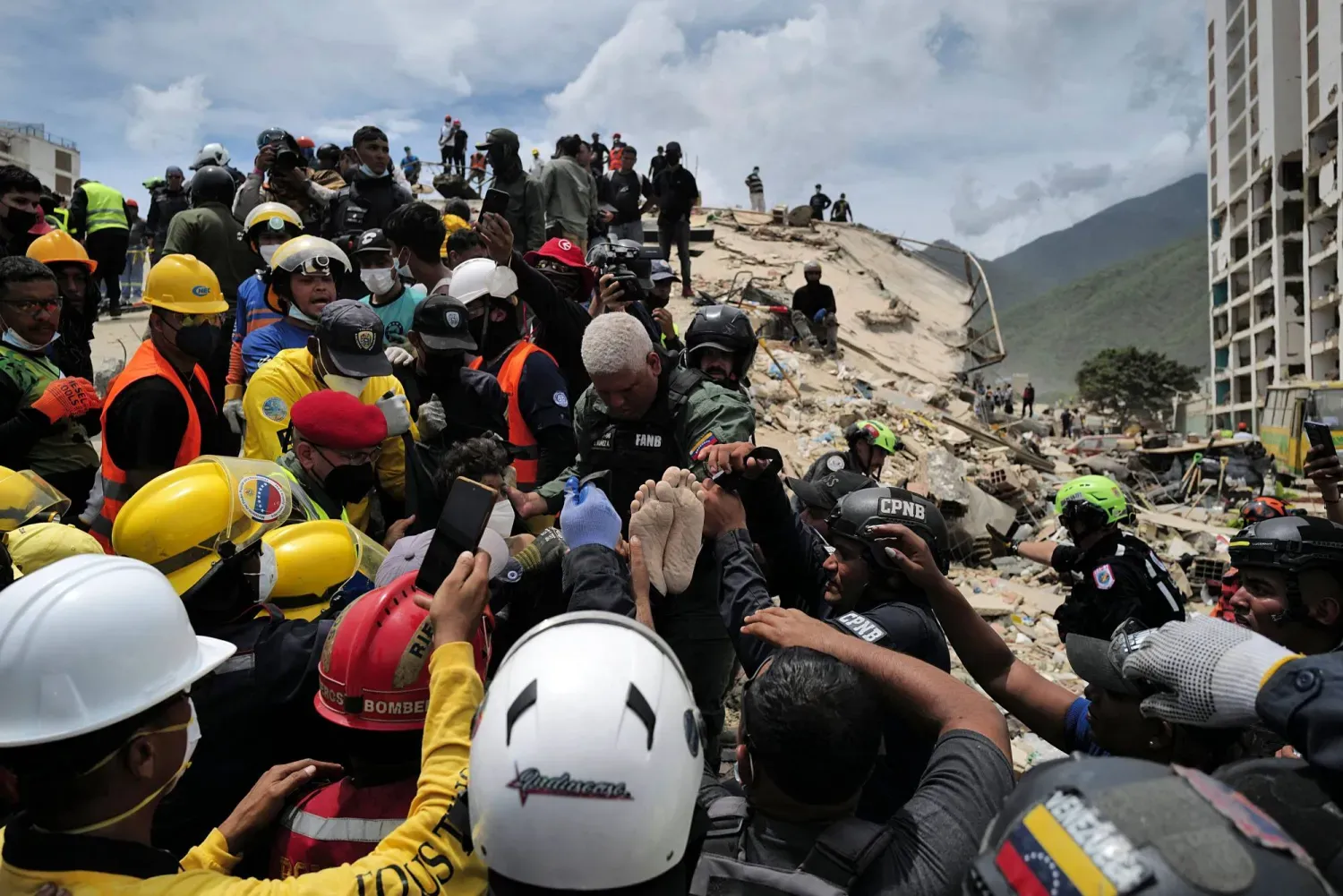 Kurtarma ekipleri La Guaira'daki enkaz altından çıkarılan bir depremzedeyi taşıyor (AFP)