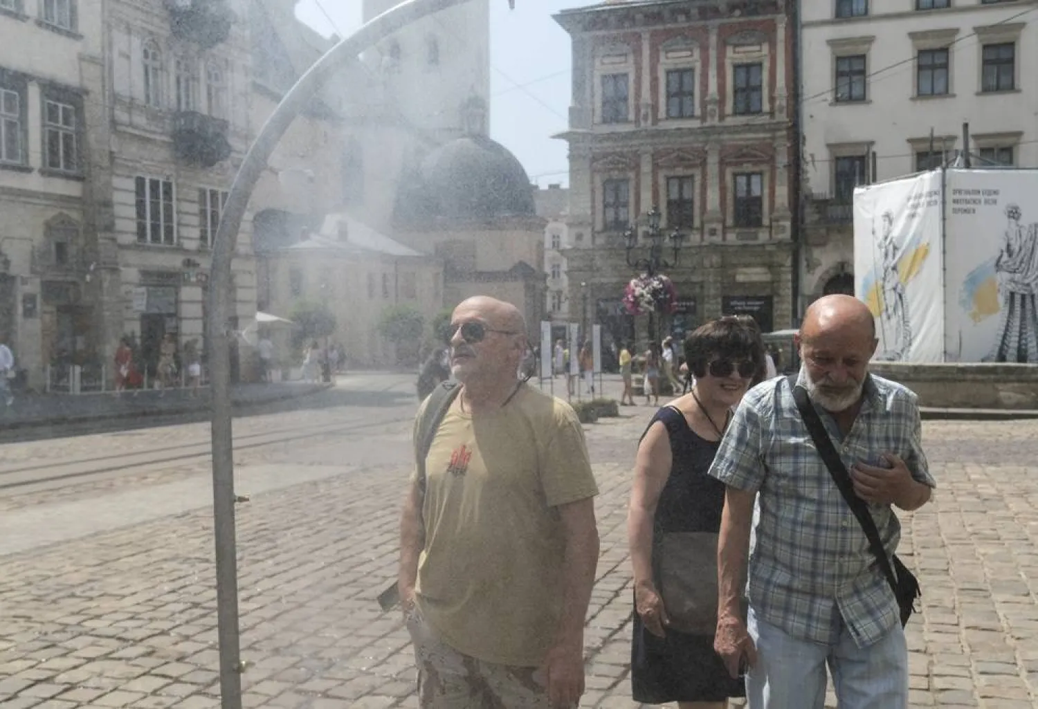 People cool themselves with water sprayed from a special sprayer set up on a sidewalk during a hot day in Lviv, Western Ukraine, 29 June 2026. (EPA)