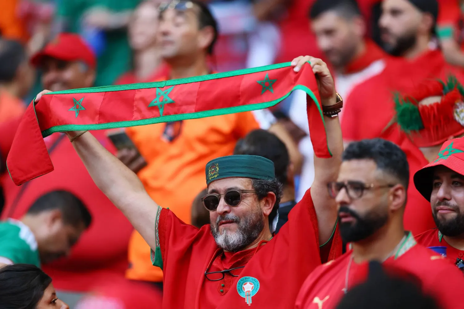 مشجع مغربي يحمل علم بلاده قبل بداية المباراة (رويترز) 