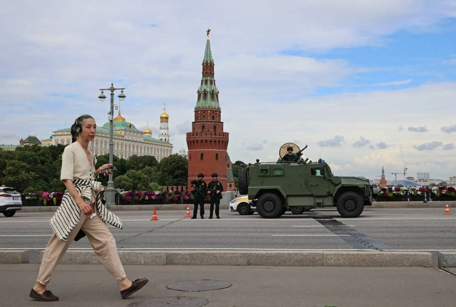 A woman walks past Russian security personnel standing guard in central Moscow, Russia June 29, 2026. (Reuters) 