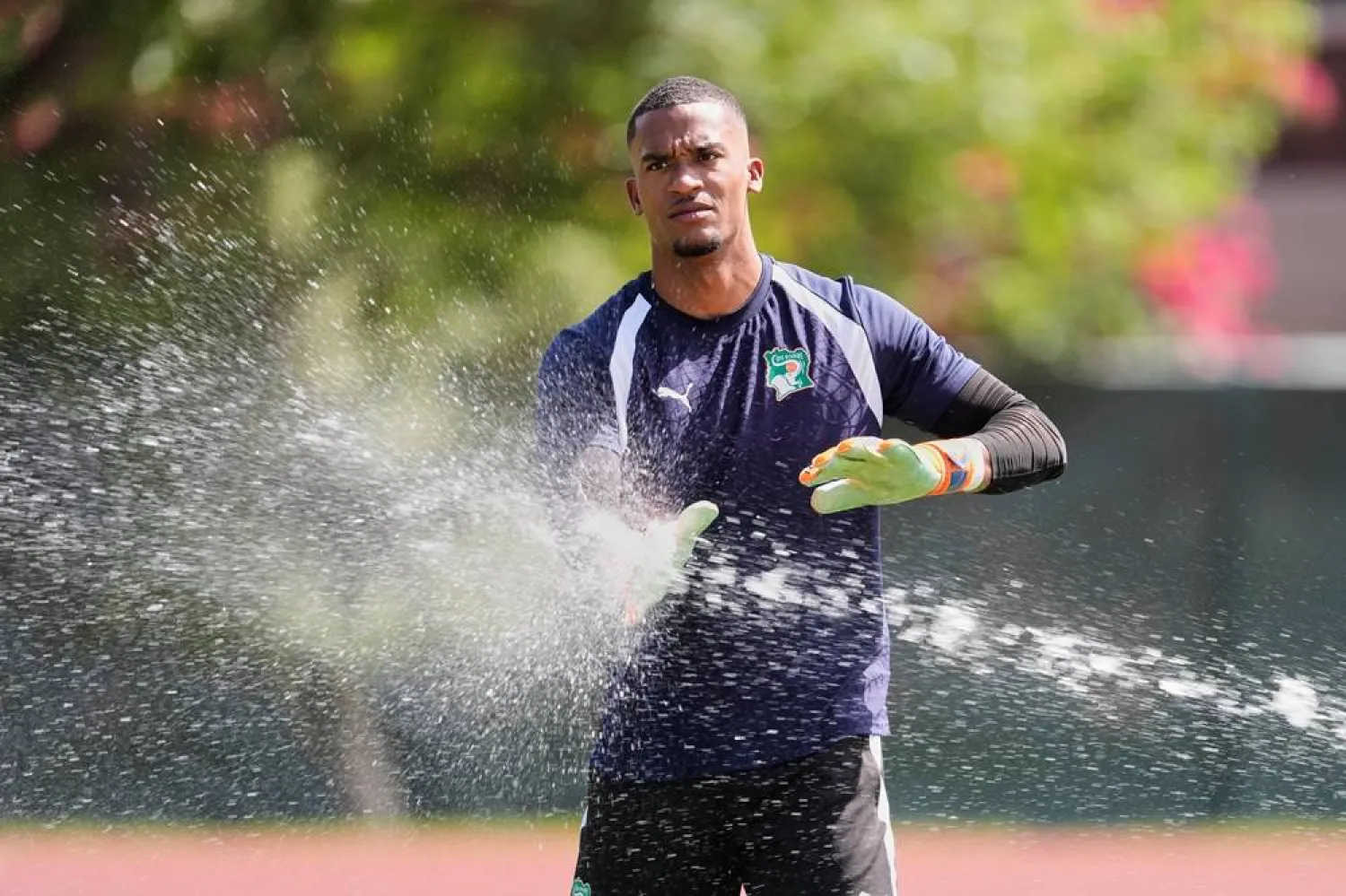  Ivory Coast goalkeeper Alban Lafont runs his hands through water from a sprinkler as he participates in a training session in Dallas, Monday, June 29, 2026, ahead of the team's World Cup soccer match against Norway. (AP) 
