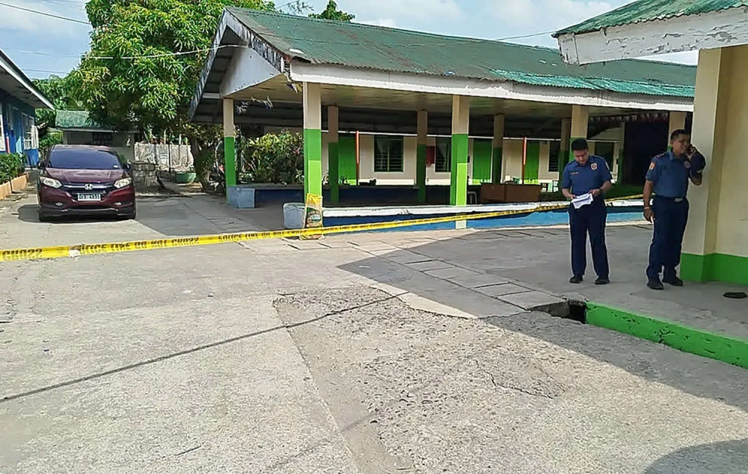 Policemen stand near the crime scene of a school compound after a shooting incident at a high school compound in Tacloban City, Leyte province on June 22, 2026. (AFP)