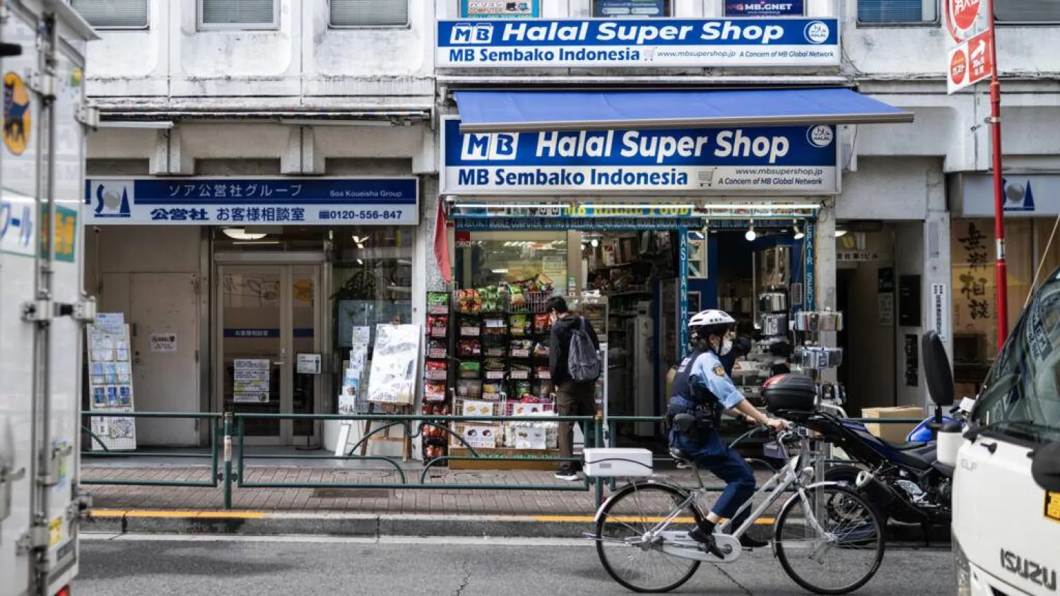 A police officer bikes past a convenience store in the Okubo–Shin area in Tokyo, a neighborhood known for its large immigrant communities. Andrew CABALLERO-REYNOLDS / AFP
