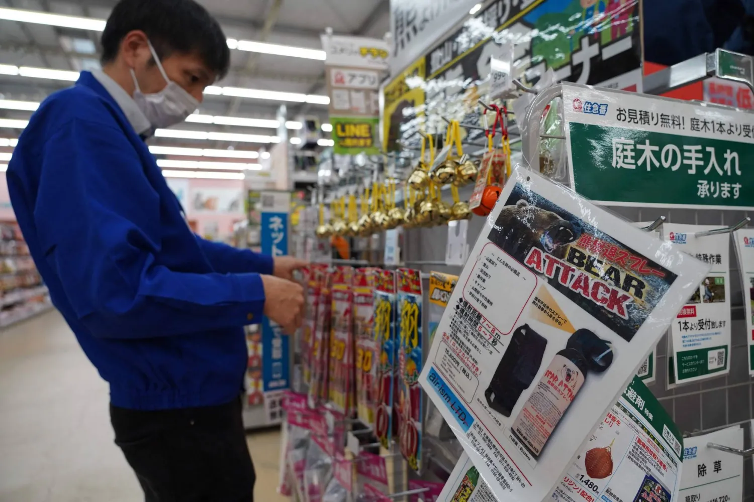 (FILES) A staff member sorts bells next to an advertisement for bear spray at a store in Hanamaki, Iwate prefecture on October 24, 2025. (Photo by Caroline GARDIN / AFP)