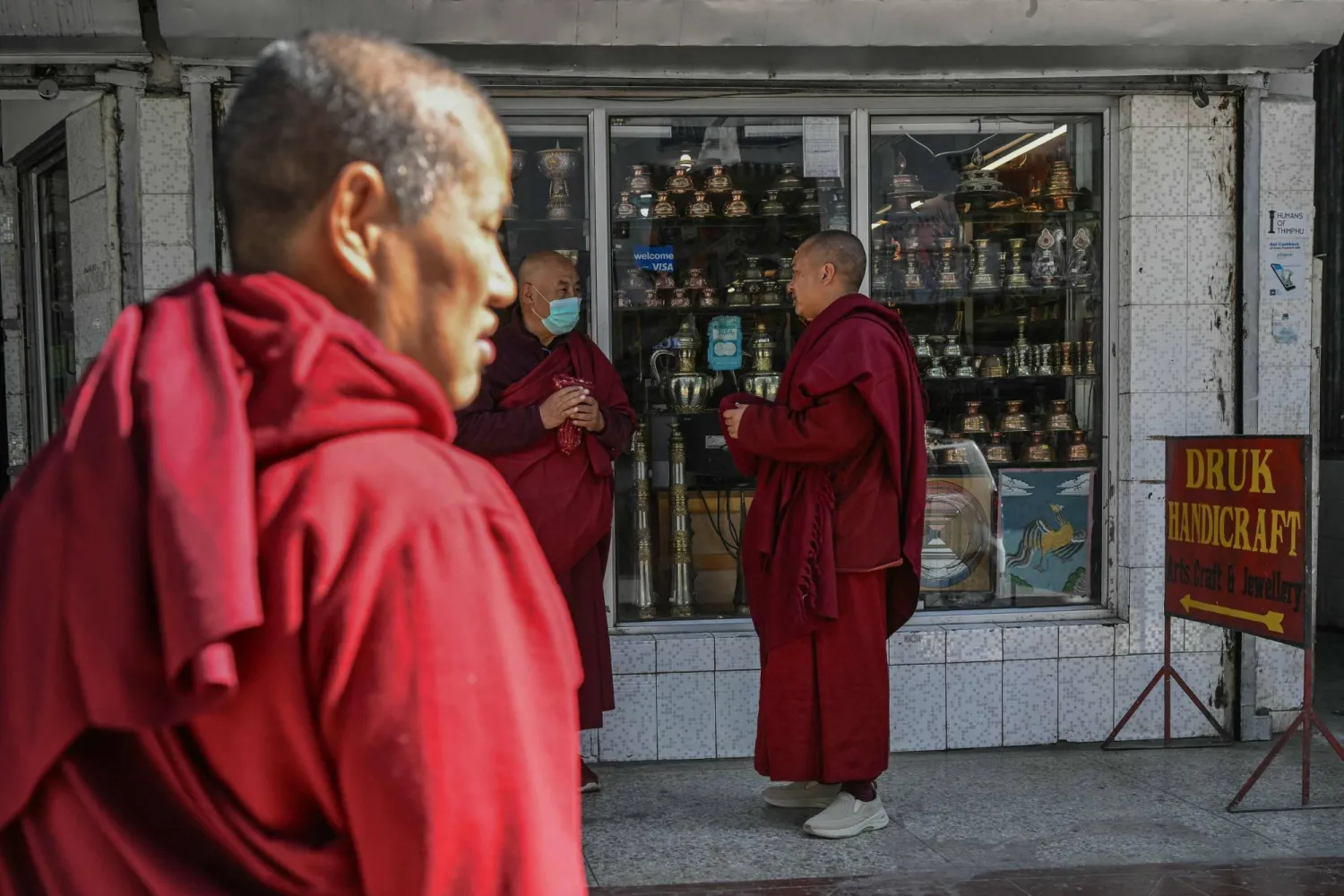(FILES) In this photograph taken on January 10, 2024, Buddhist monks stand outside a shop at a market area in Bhutan's capital Thimphu. (Photo by Money SHARMA / AFP)