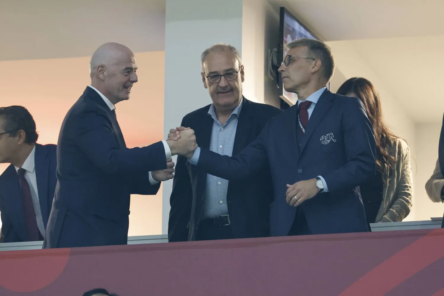 يصافح رئيس الاتحاد الدولي لكرة القدم (فيفا) جياني إنفانتينو (يساراً) كلاً من بيتر كنابل رئيس الاتحاد السويسري لكرة القدم (يميناً) وغي بارميلان الرئيس السويسري (وسط) (إ.ب.أ) 