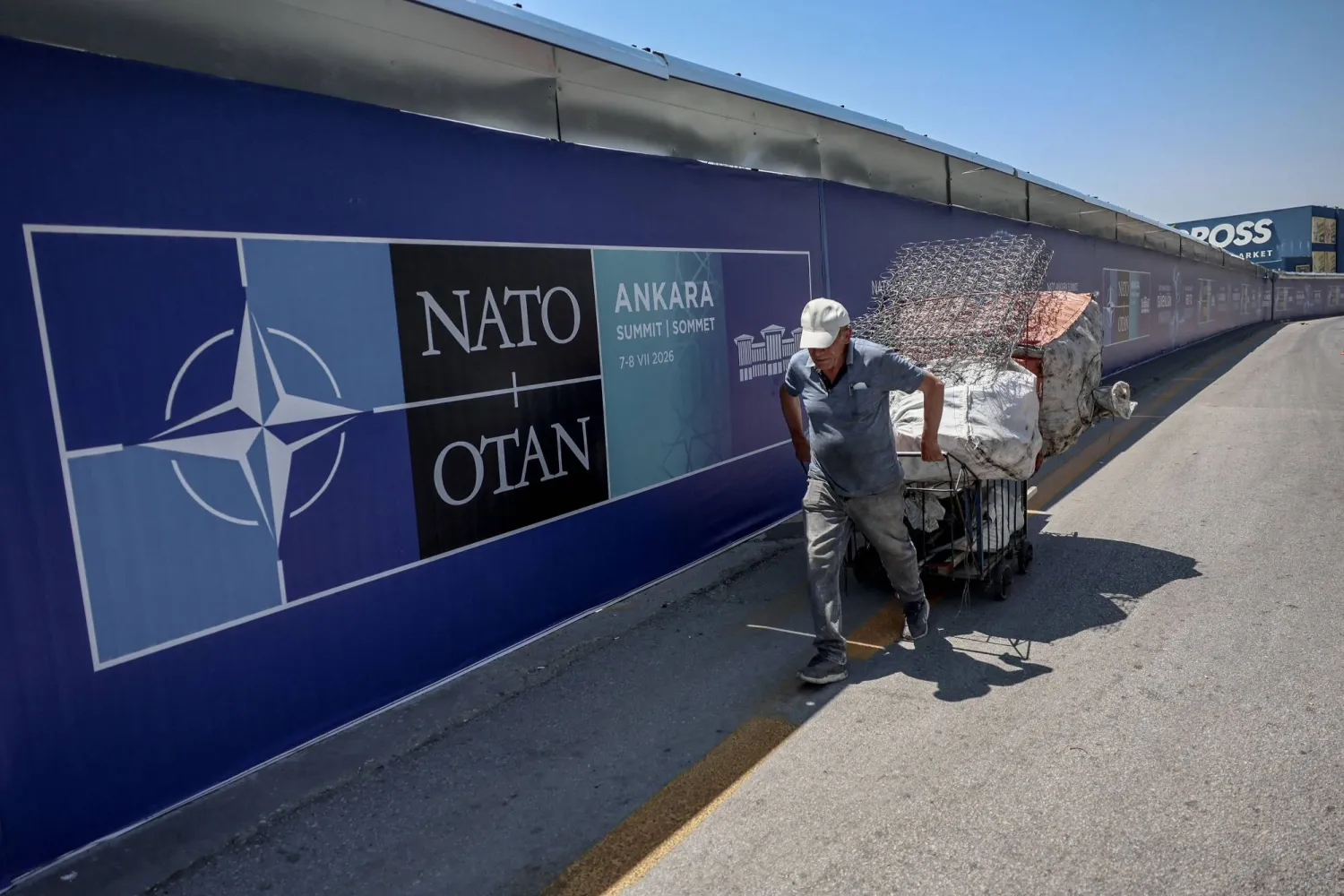  A paper collector pulls his handcart past billboards displayed along the boulevard on the protocol route ahead of the NATO Summit in Ankara, on July 2, 2026. (AFP)