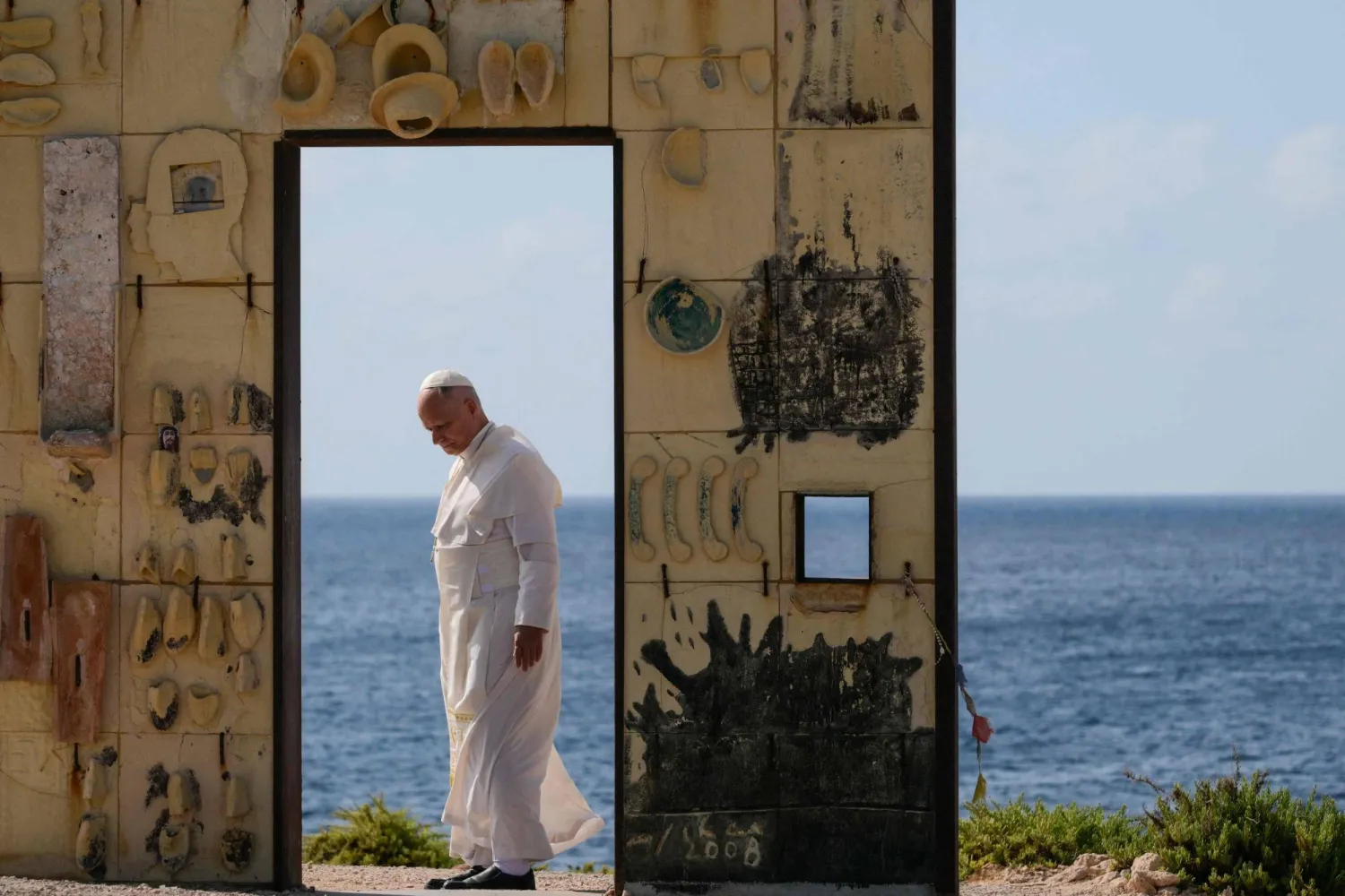 Pope Leo XIV walks trough the arch of the monument Door of Europe - Porta d'Europa made by the italian artist Mimmo Paladino, during a one day visit to Lampedusa island, south of Sicily, on July 4, 2026. (Photo by Tiziana FABI / AFP)