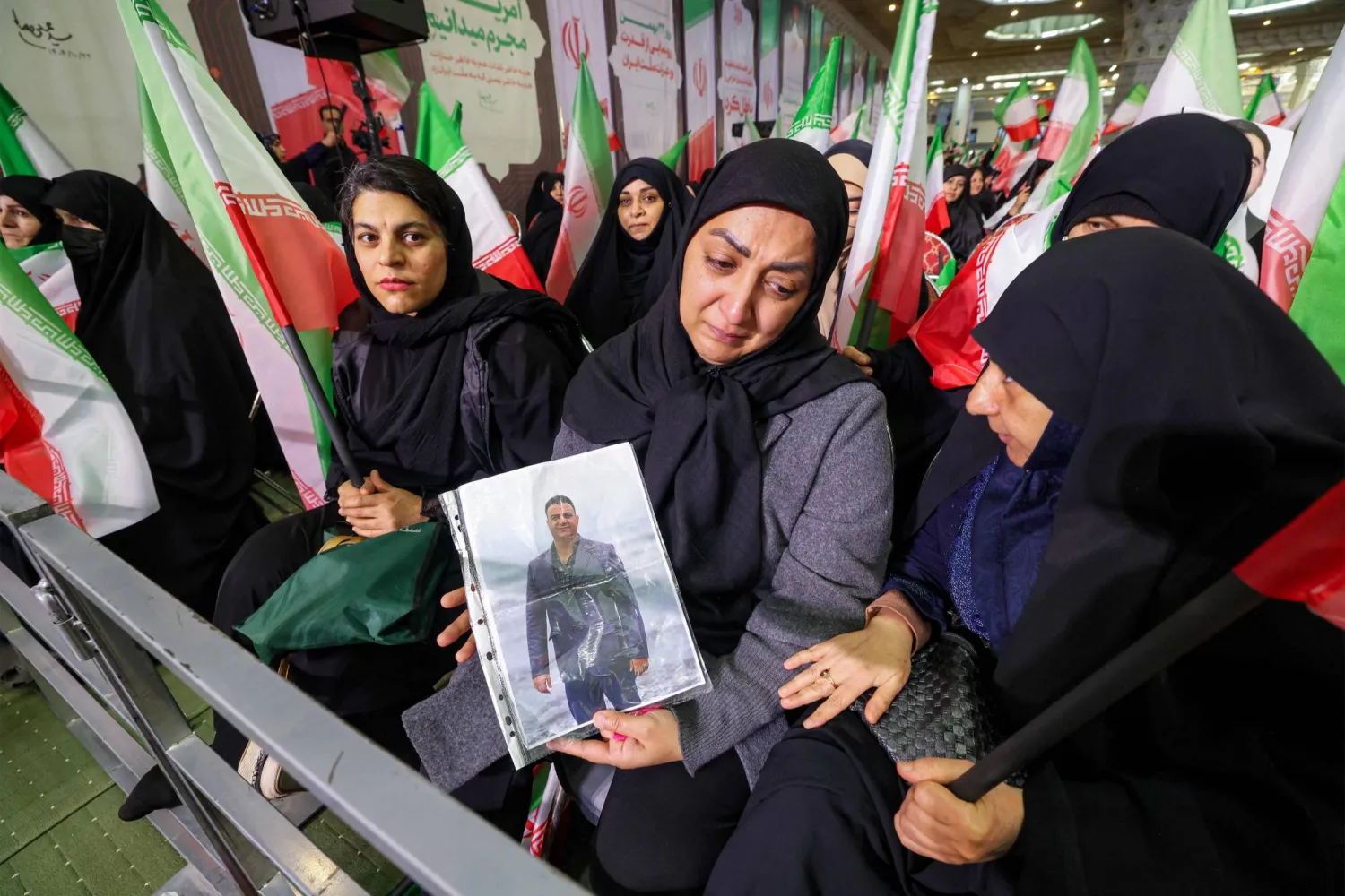 امرأة في طهران تحمل صورة لشخص قُتل في احتجاجات سابقة مناهضة للحكومة في إيران (أ.ف.ب)