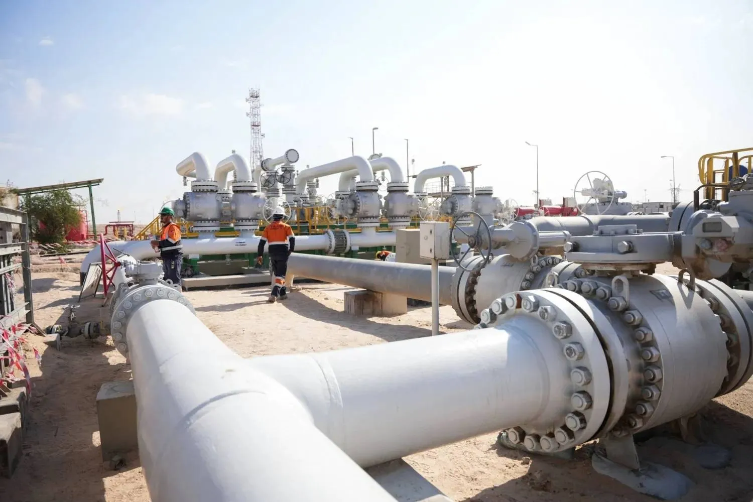 Workers walk across pipelines at the Rumaila oil field in Basra, Iraq (Reuters)