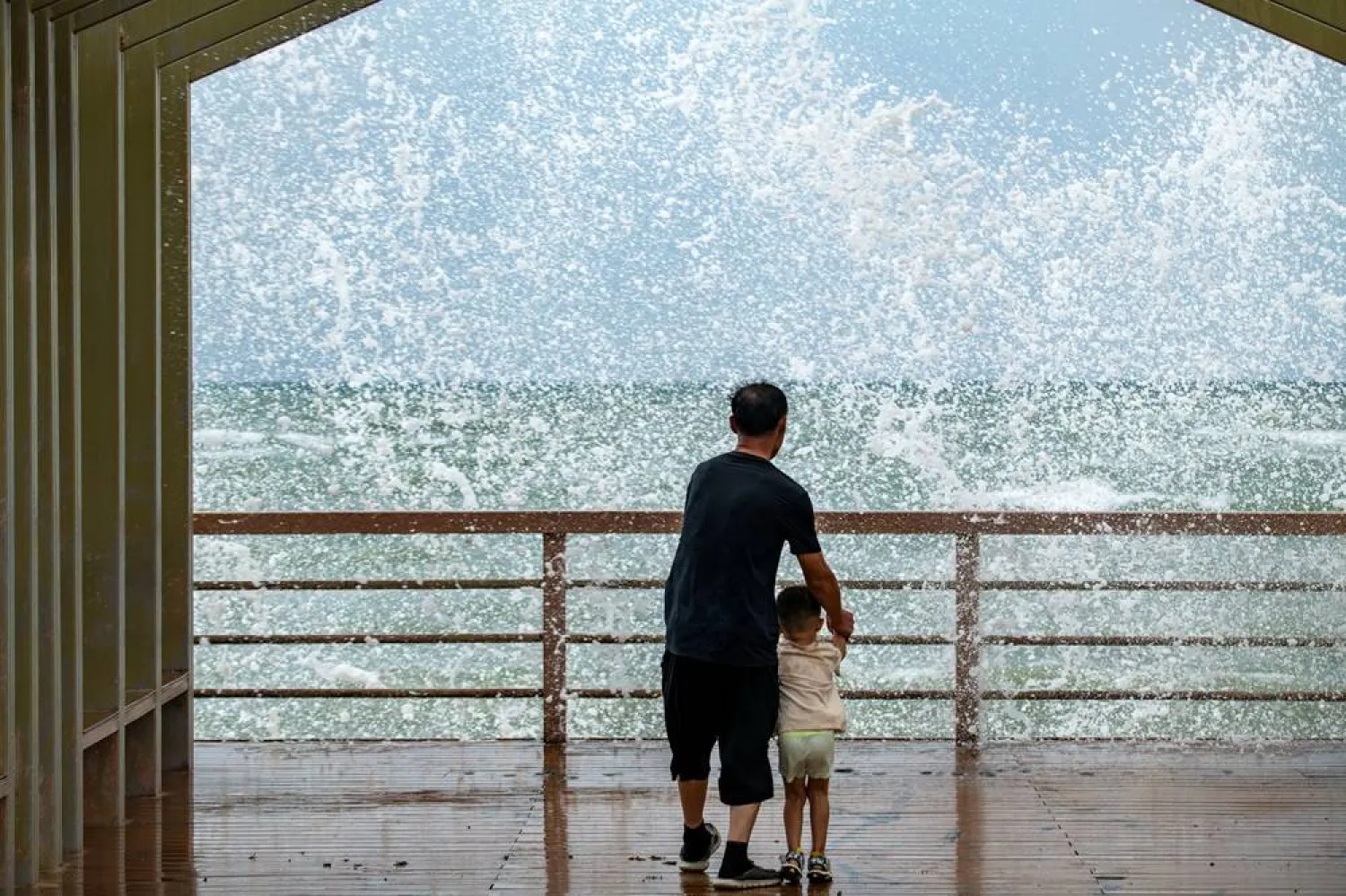 People watch waves crashing against the shore as Tropical Storm Maysak approaches in Boao, Qionghai, Hainan province, China, July 3, 2026. (cnsphoto via Reuters)
