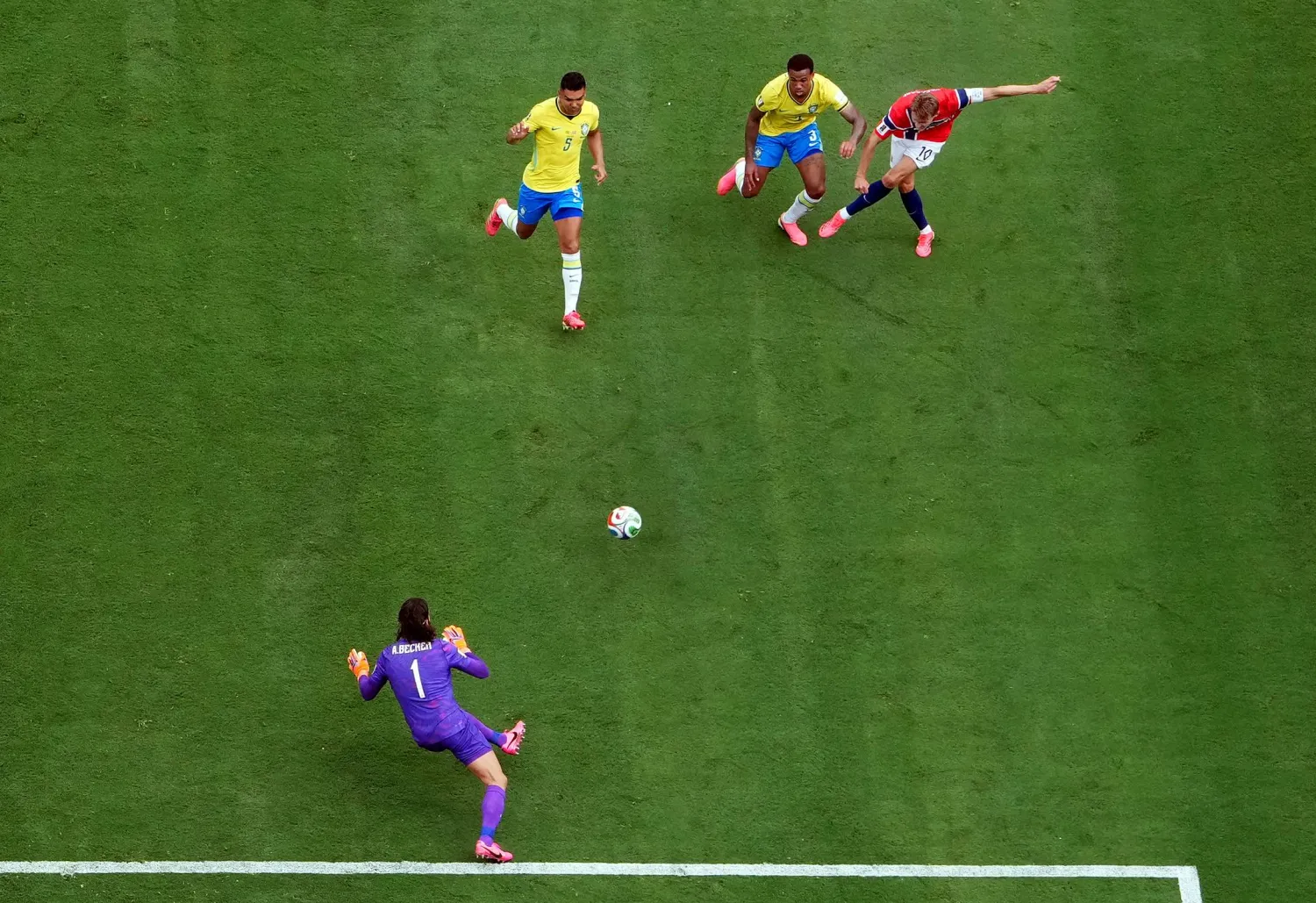 الحارس البرازيلي أليسون بيكر يتصدى لتسديدة من اللاعب النرويجي مارتن أوديغارد (رويترز)