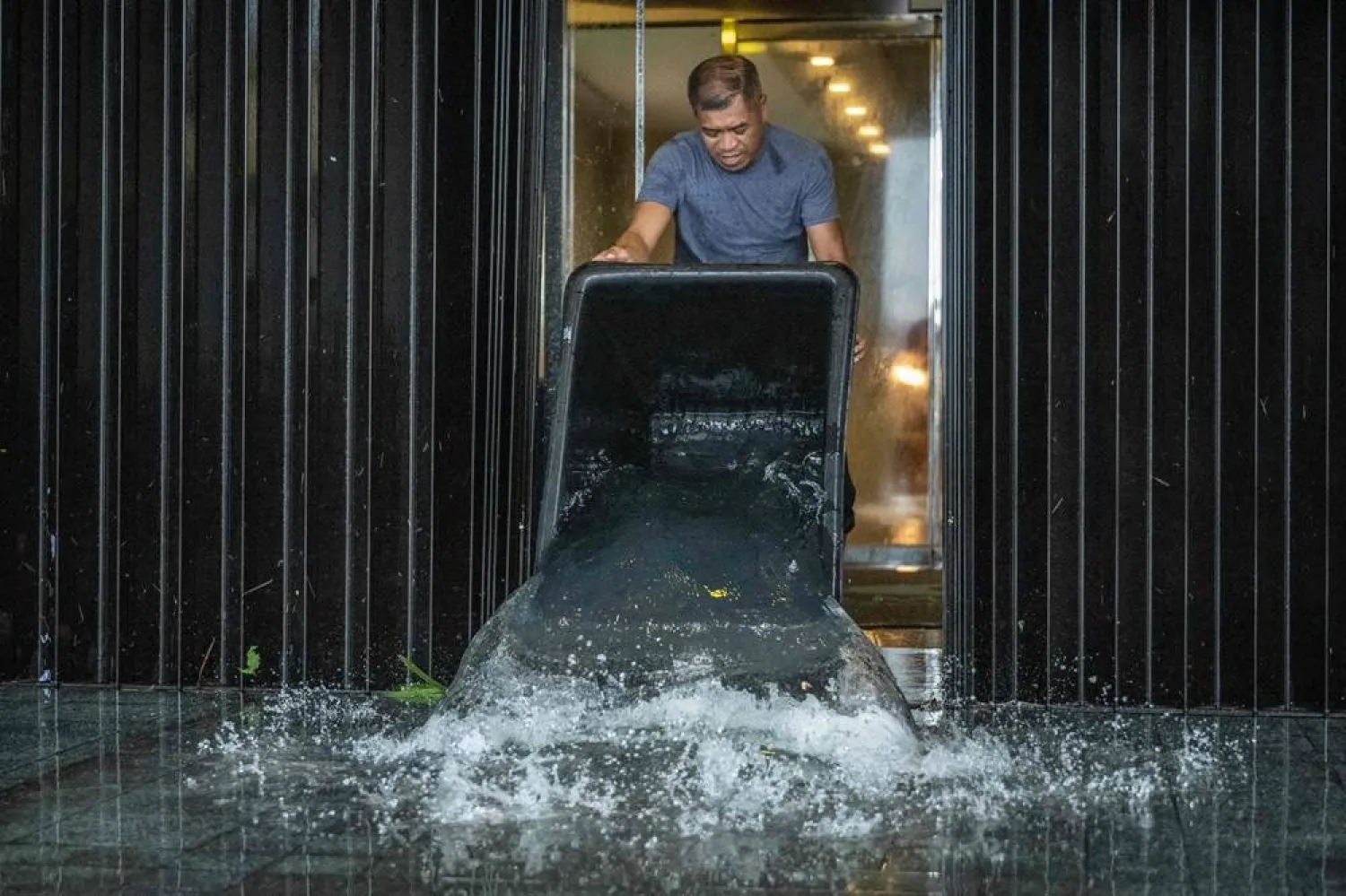 A hotel staff member removes water that leaked into a building during heavy rain brought by Super Typhoon Bavi in Guam on July 6, 2026. (AFP) 
