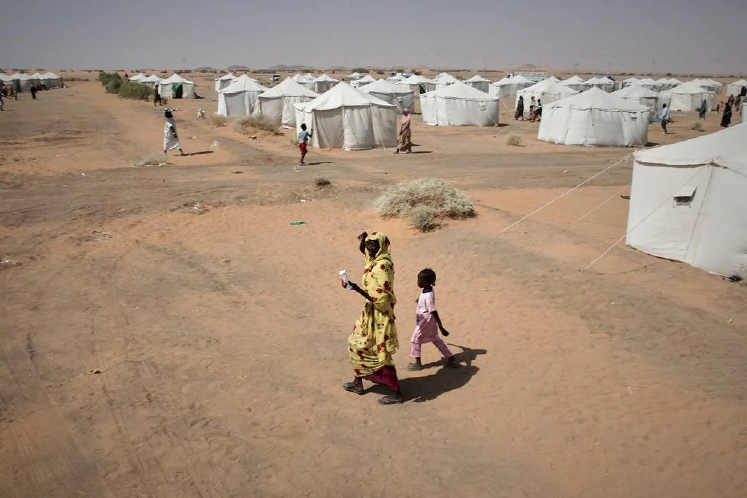 A woman and a child, displaced from North Darfur's capital, al-Fashiar or other conflict-affected areas walk in the newly established el-Afadh camp in al-Dabbah, in Sudan's Northern State, Sudan, Thursday, Nov. 13, 2025. (AP)