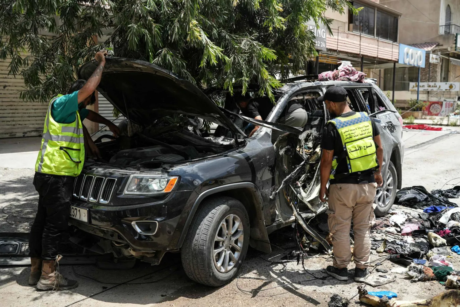 مسعفون وعناصر إنقاذ يعاينون السيارة التي استهدفت بغارة إسرائيلية في النبطية بجنوب لبنان وأدت إلى مقتل 4 أشخاص (أ.ف.ب)