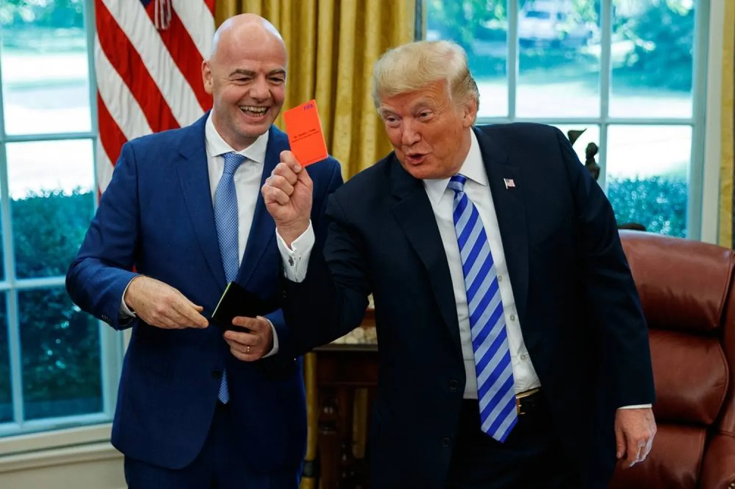 President Donald Trump holds up a red card during a meeting with FIFA president Gianni Infantino in the Oval Office of the White House, Tuesday, Aug. 28, 2018, in Washington. (AP)