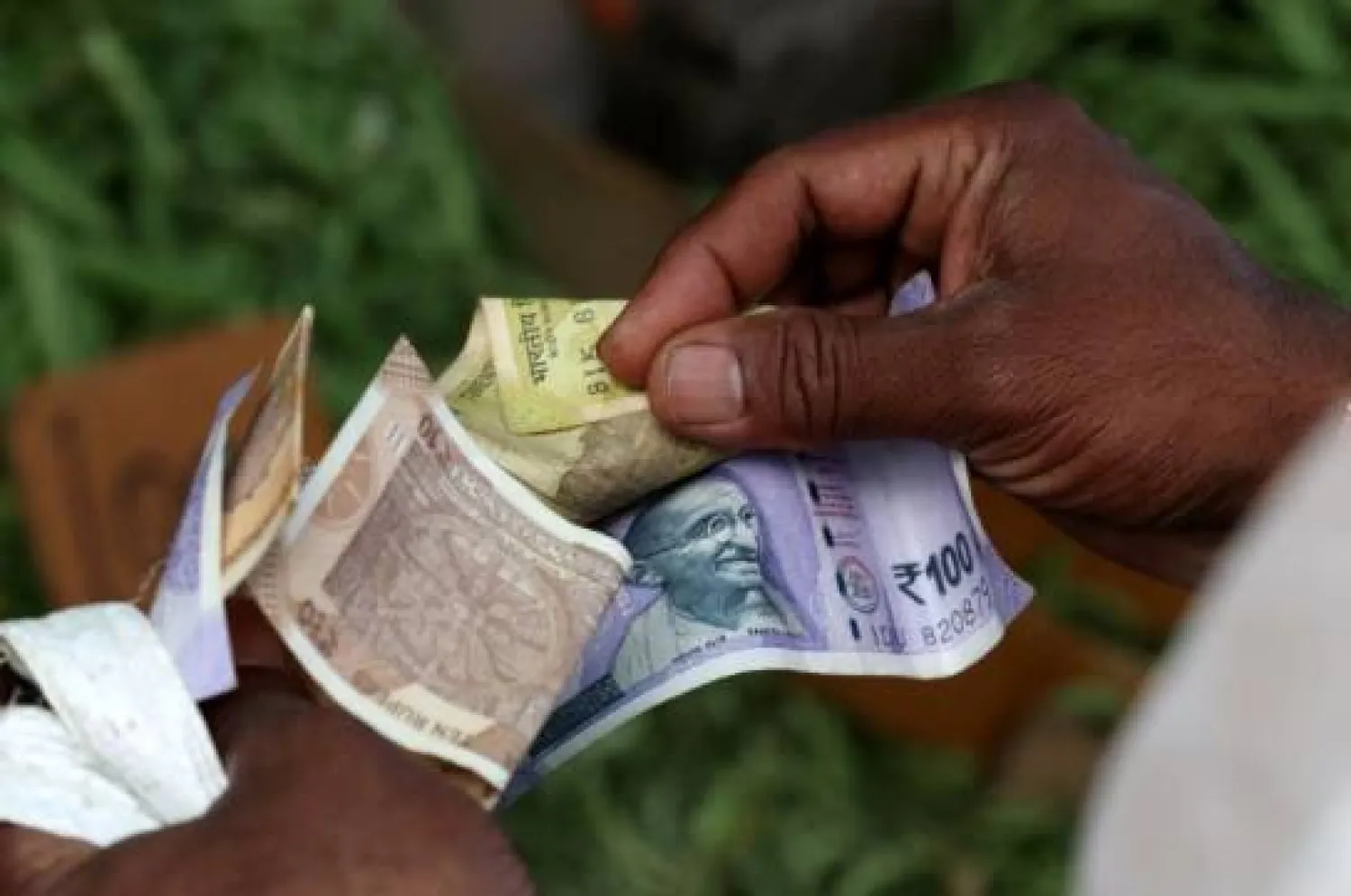 رجل يعد أوراقاً نقدية هندية في إحدى الأسواق بمدينة بنغالورو (رويترز)