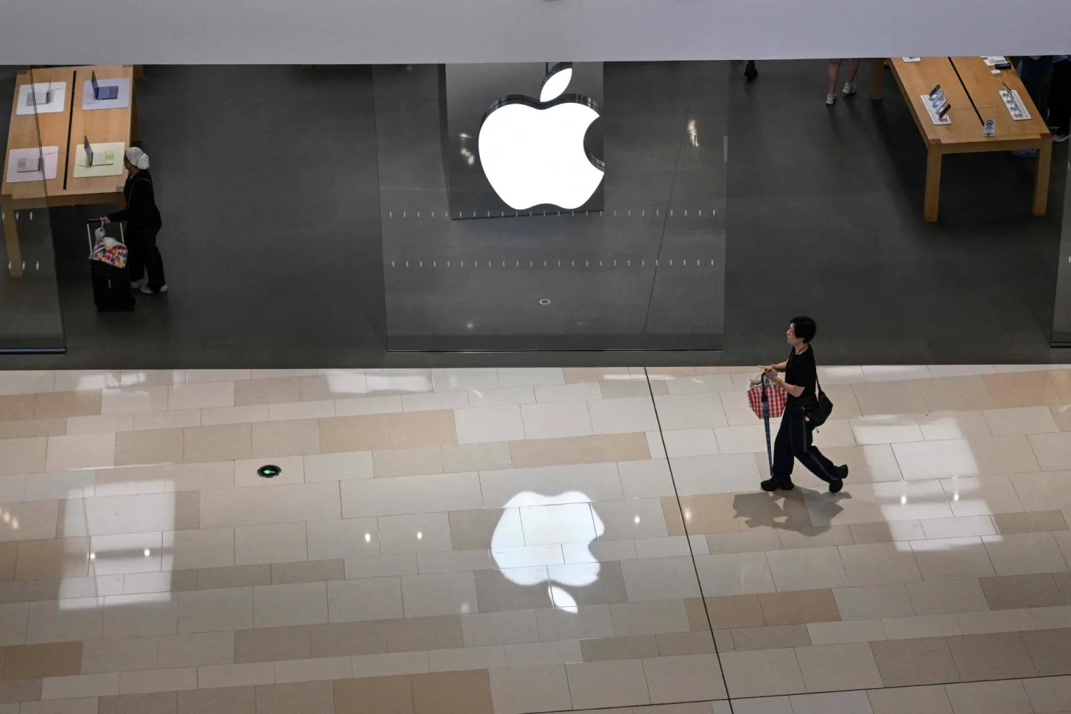 People walk past an Apple store in a shopping mall in the Xuhui district in Shanghai on July 1, 2026. (Photo by Hector RETAMAL / AFP)