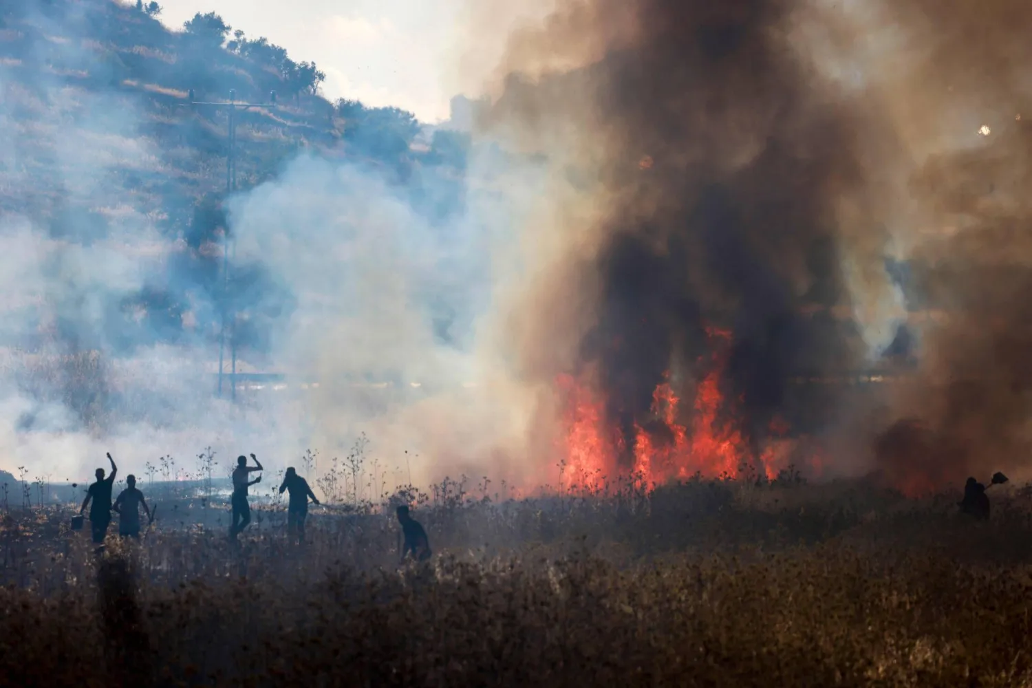 فلسطينيون يحاولون إخماد حريق أشعله مستوطنون في حقول قمح بقرية سالم شرق نابلس في الضفة الغربية المحتلة يوم الجمعة (أ.ف.ب)