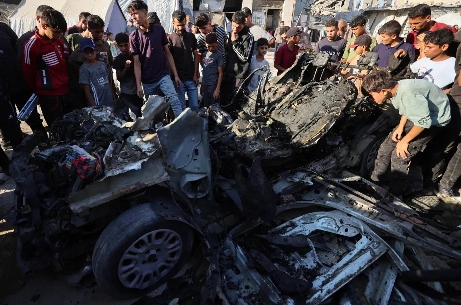 Filistinliler, İsrail'in Gazze kentinde bir aracı hedef aldığı hava saldırısının ardından olay yerini inceledi. (Reuters)