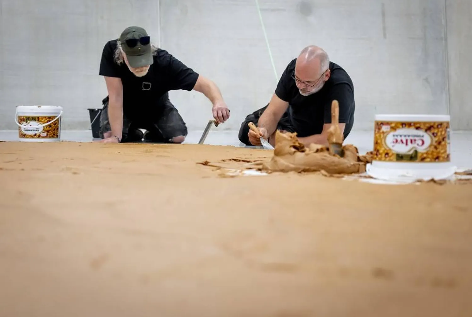 "Peanut Butter Plasterers" are spreading a floor of peanut butter, without chunks, in the Depot of Museum Boijmans Van Beuningen, in Rotterdam, Netherlands, 03 July 2026, as a tribute to the late artist and TV producer Wim T. Schippers. (EPA)