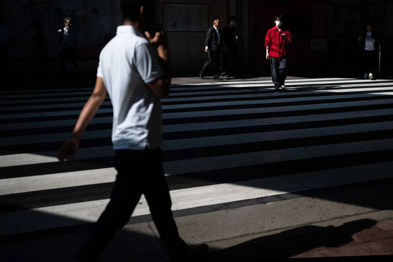 People cross an intersection near Okubo metro station, one stop north of Shinjuku metro, in Tokyo on June 12, 2026, in the Okubo亡hin area, a neighbourhood known for its large immigrant communities, including Korean, Southeast Asian and South Asian residents. (Photo by Andrew CABALLERO-REYNOLDS / AFP)
